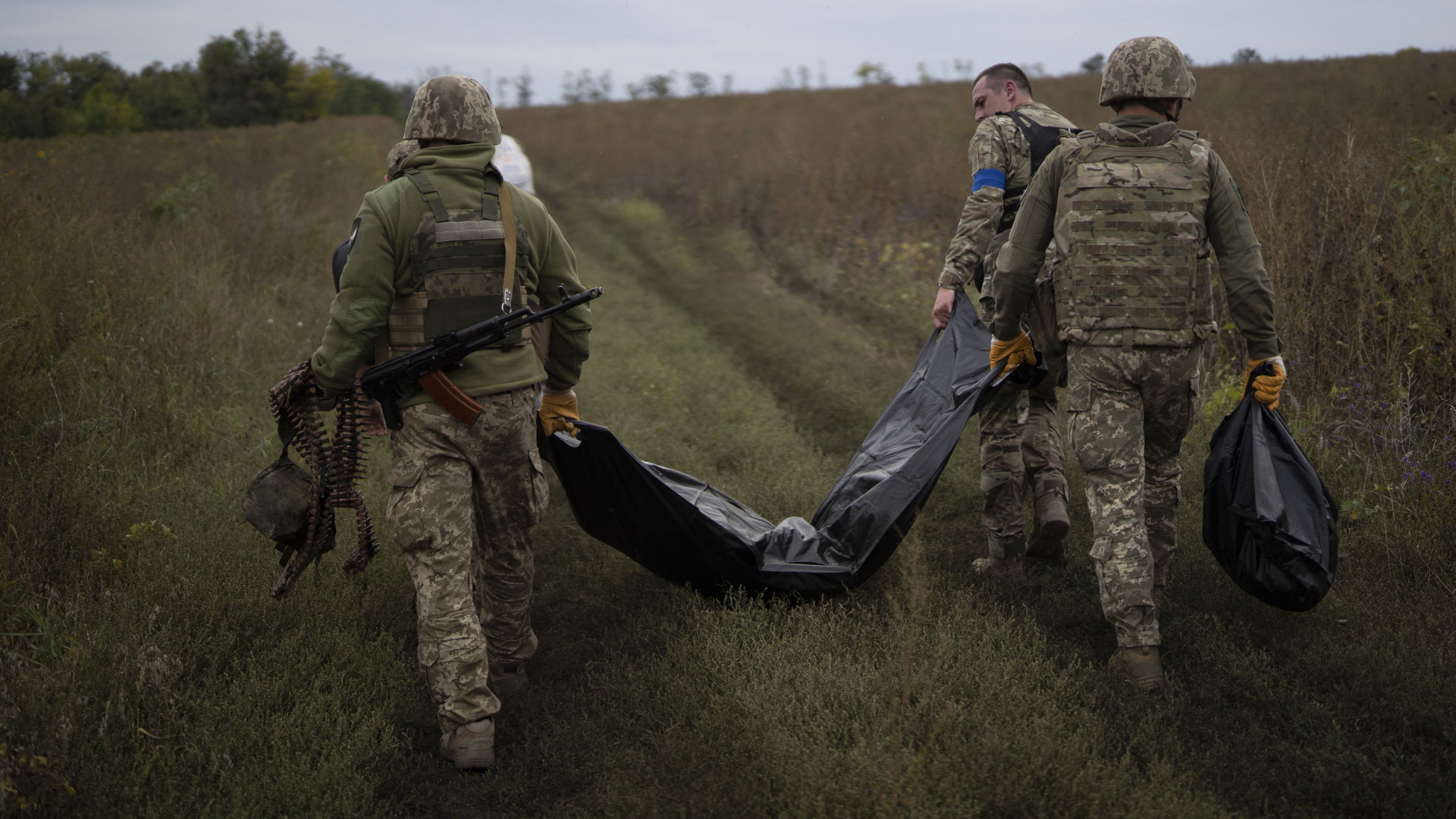 Ukrainische Soldaten tragen in der Region Charkiw Säcke mit den Leichen gefallener Soldaten. | AP