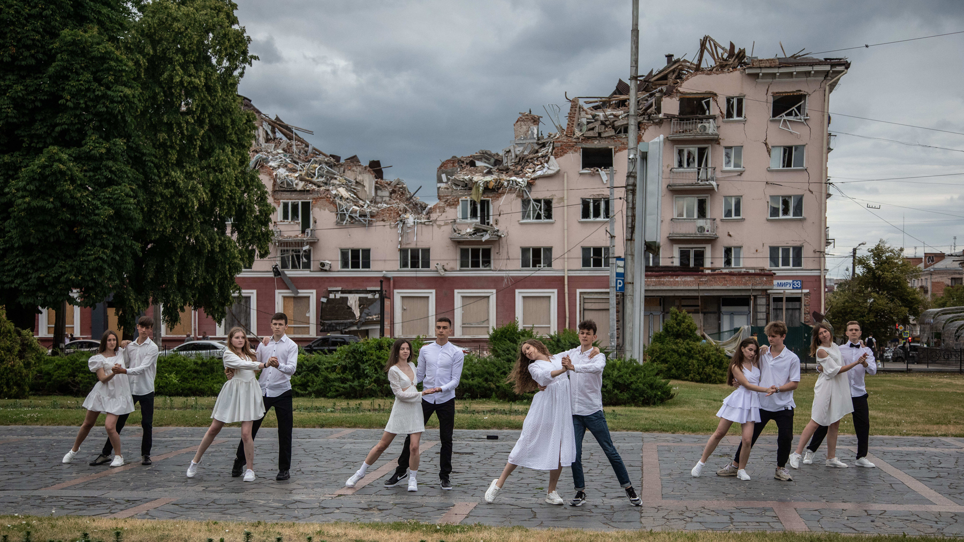 Eine Tanzgruppe junger Schulabsolventen vor dem zerstörten "Hotel Ukraina" in Tschernihiw posiert in Formation.