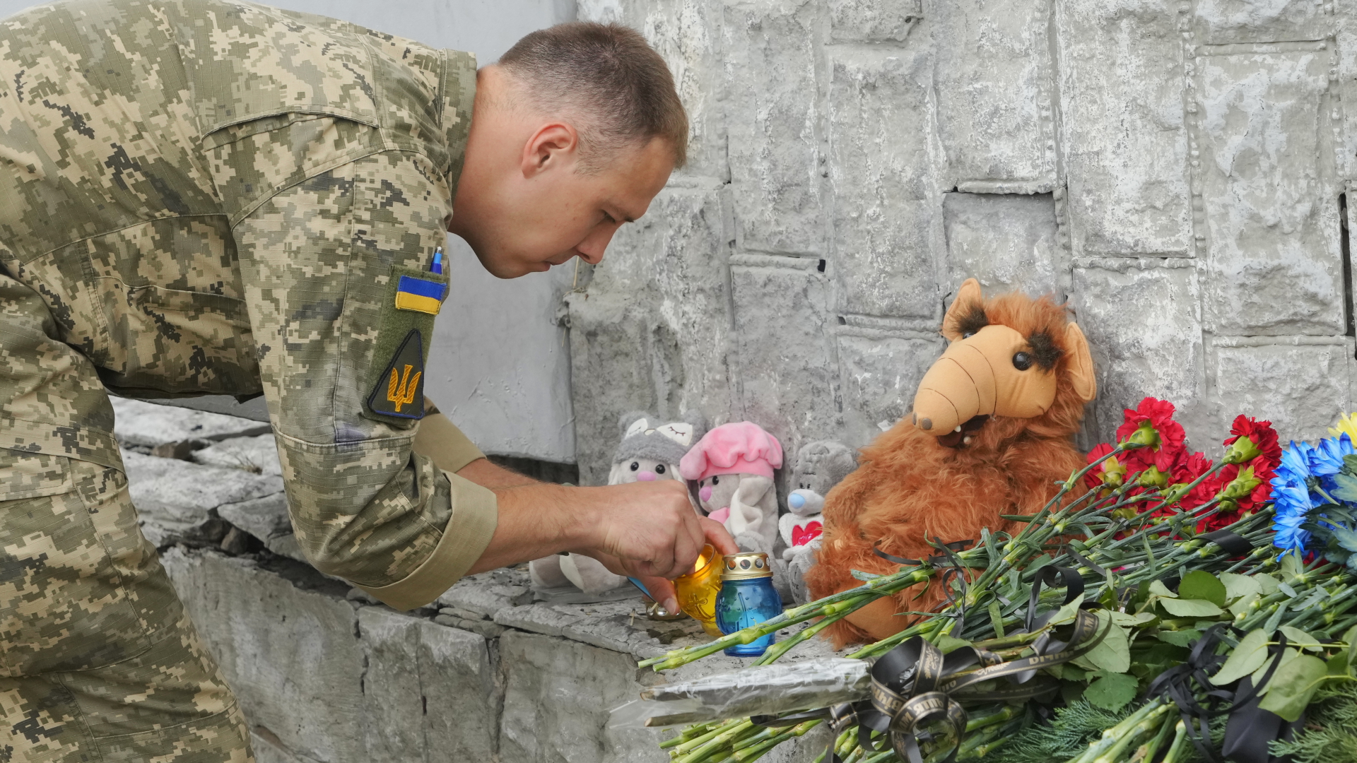 Ein ukrainischer Soldat zündet eine Gedenkkerze in Winnyzja an. | dpa