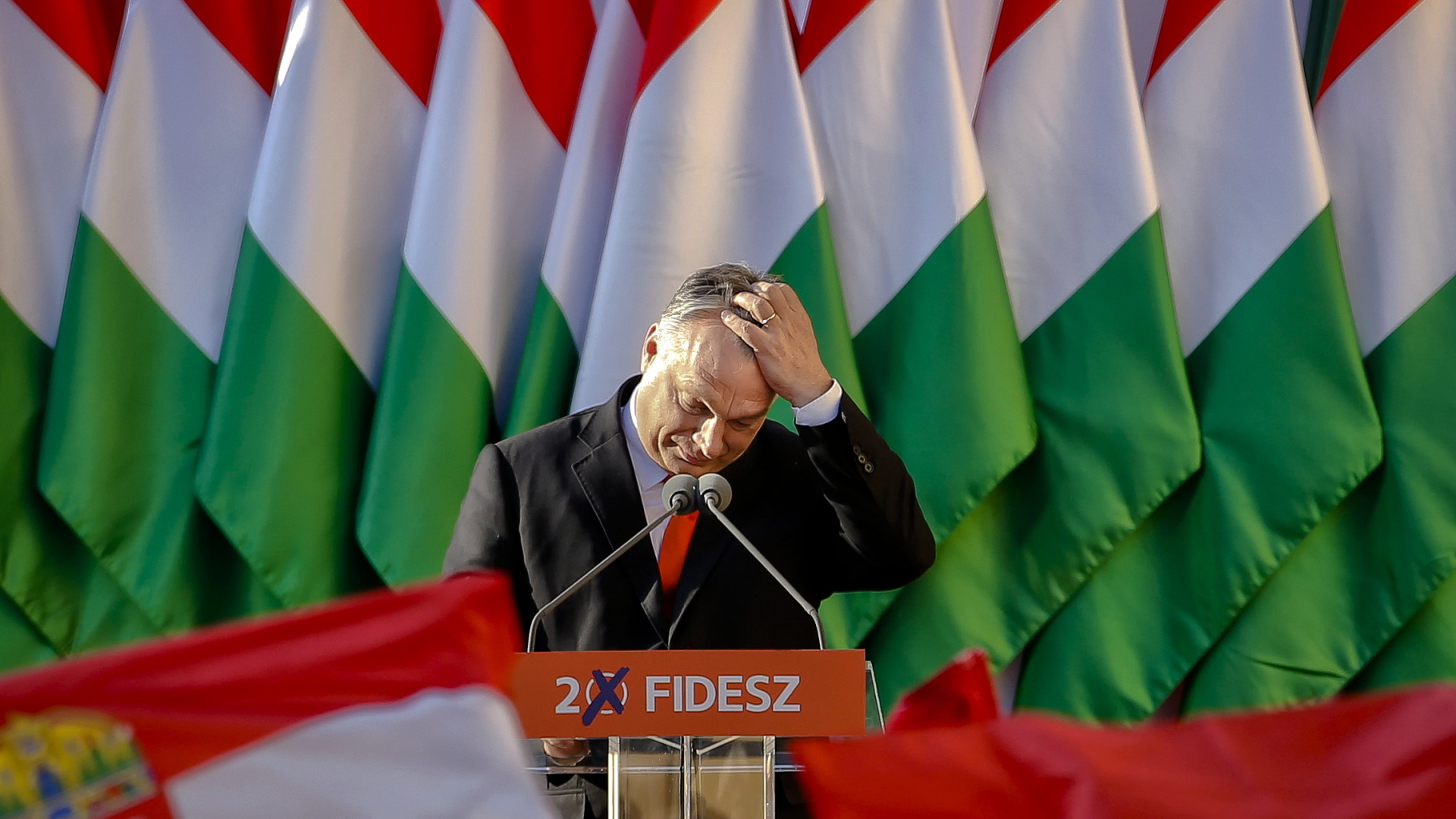 Ungarns Präsident Viktor Orban blickt vor einem Rednerpult nach unten und fährt sich durch die Haare. | dpa