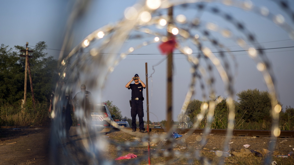 Polizisten an der ungarisch-serbischen Grenze. Ein Stacheldrahtzaun soll Flüchtlinge stoppen. | AP