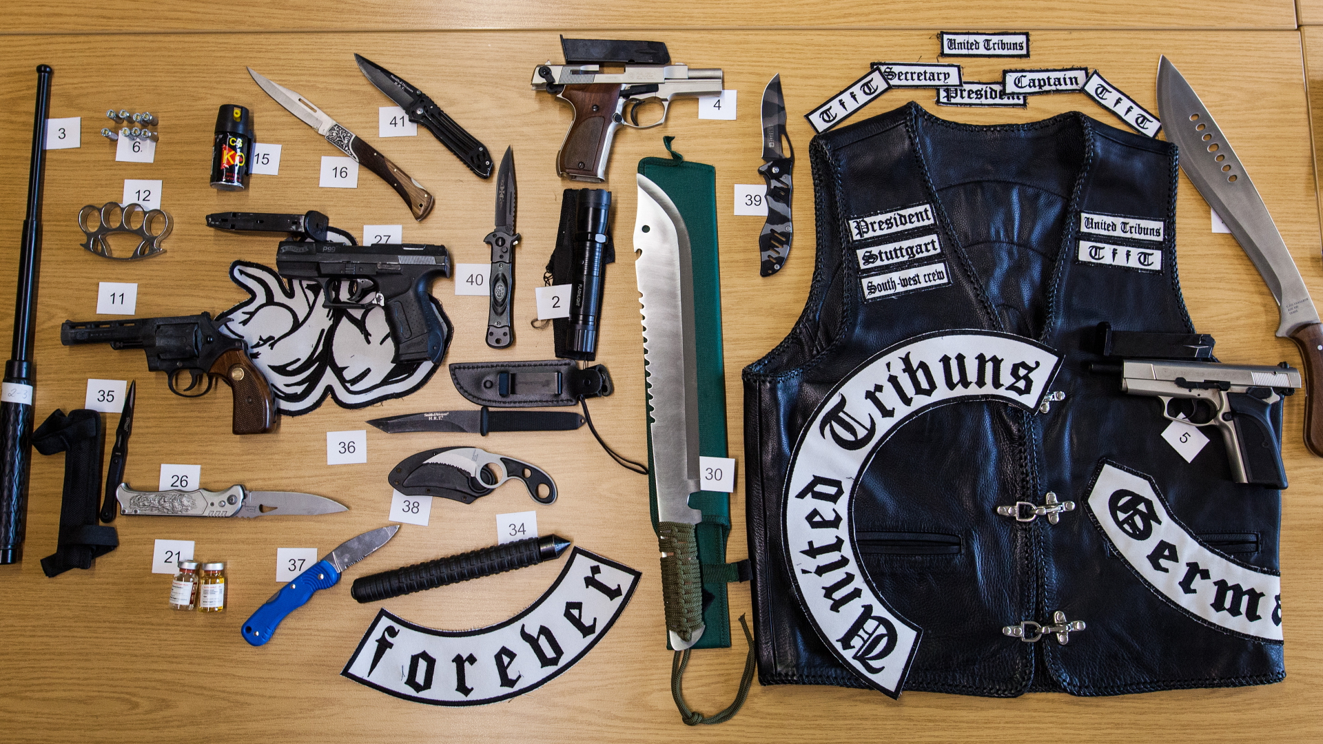 Zahlreiche beschlagnahmte Waffen und eine Leder-Jacke liegen auf einem Tisch im Polizeipräsidium. | dpa
