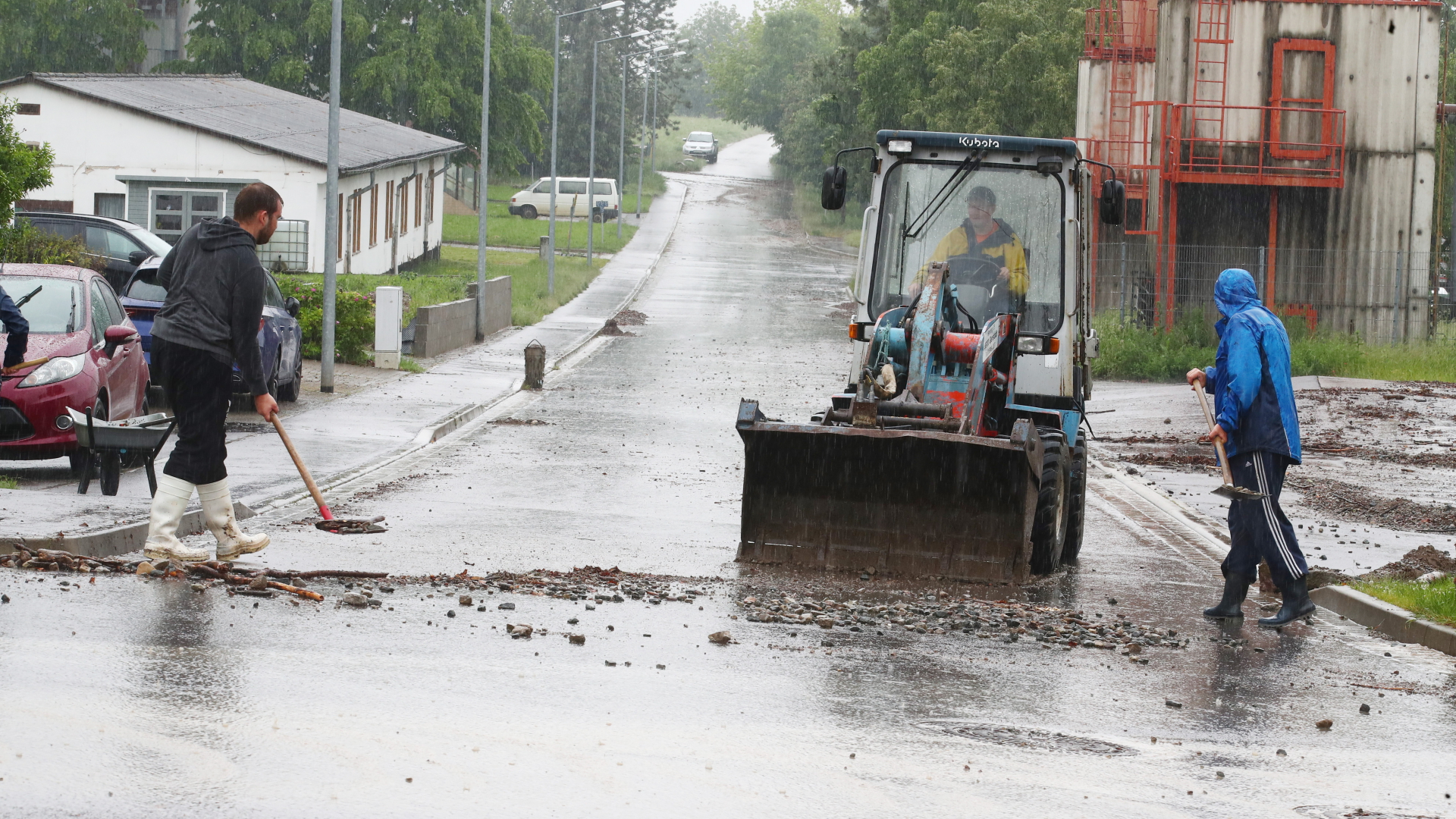 Helfer beseitigen im thüringischen Gierstädt den durch heftige Regenfälle angespülten Schlamm von den Straßen. | dpa
