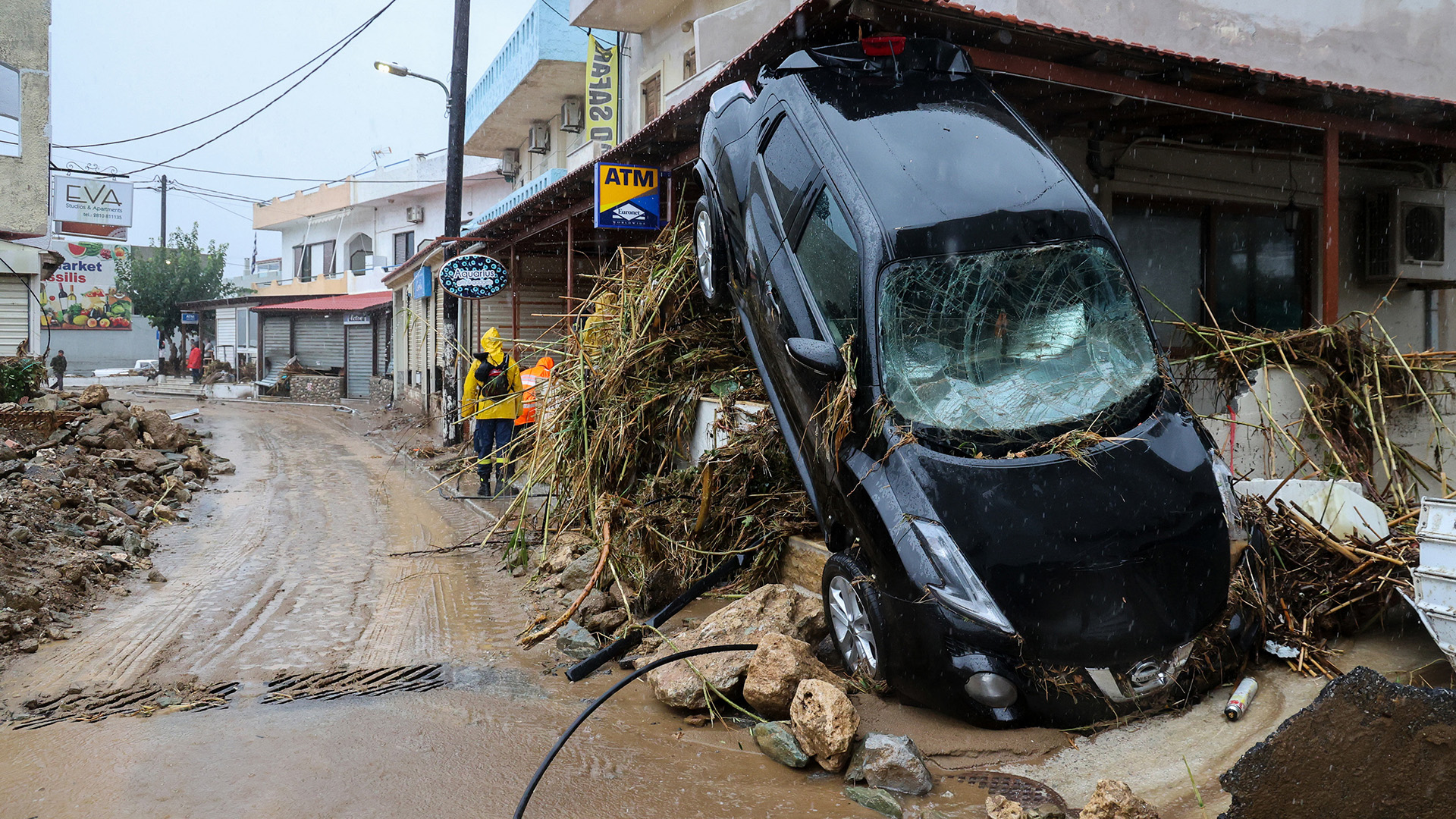 Ein zerstörtes Auto, das von den Wassermassen weggetragen wurde, liegt auf einem Trümmerhaufen. | dpa