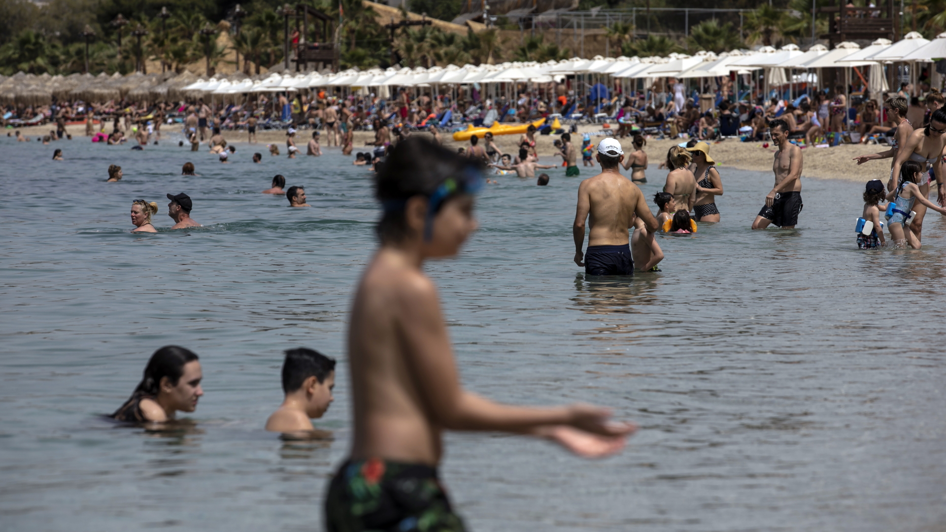 Menschen baden im Mittelmeer am Strand von Alimos in der Nähe von Athen. | dpa