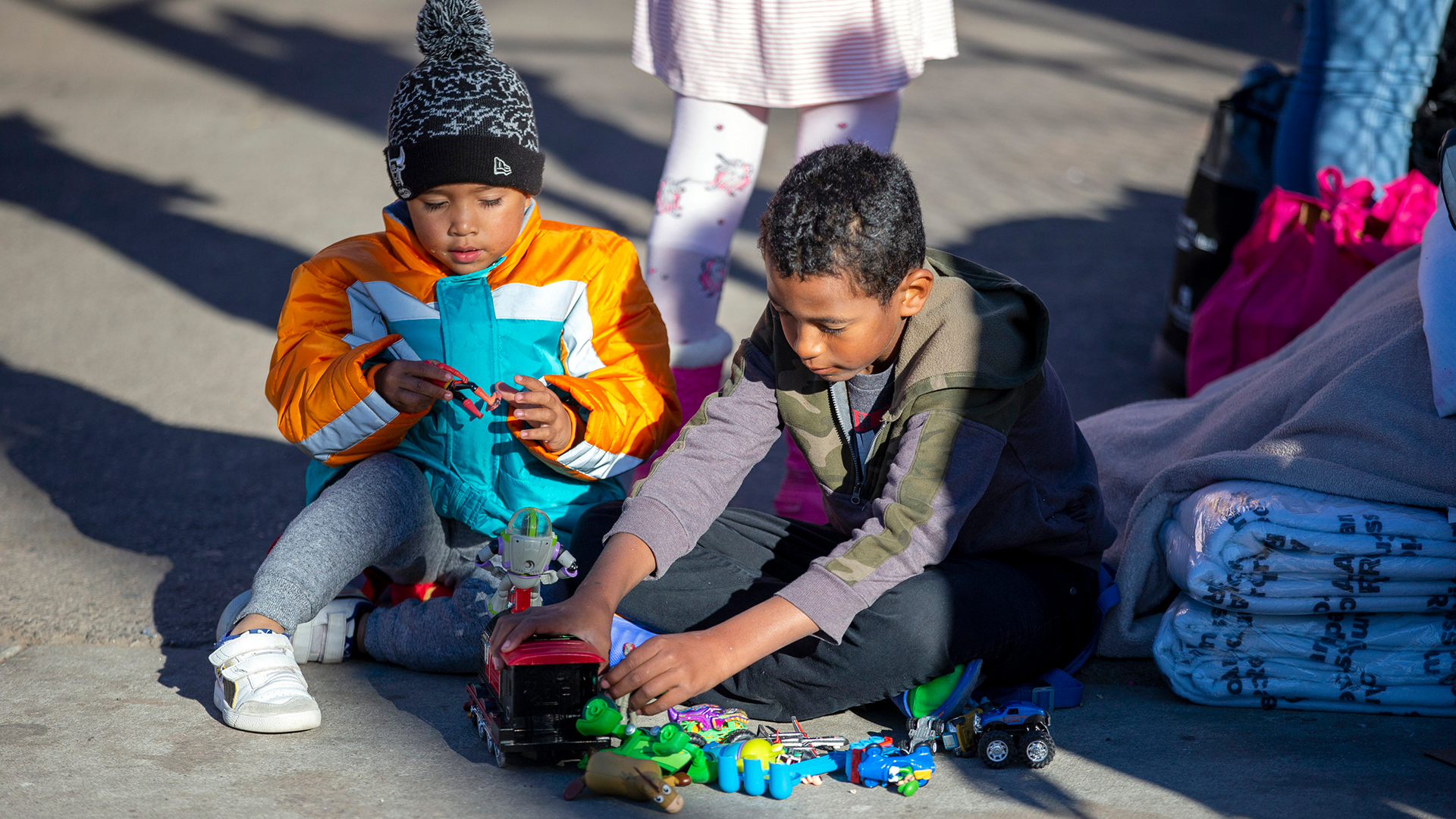 Zwei geflohene Kinder sitzen auf dem Boden vor einer Kirche in Texas und spielen. | AP