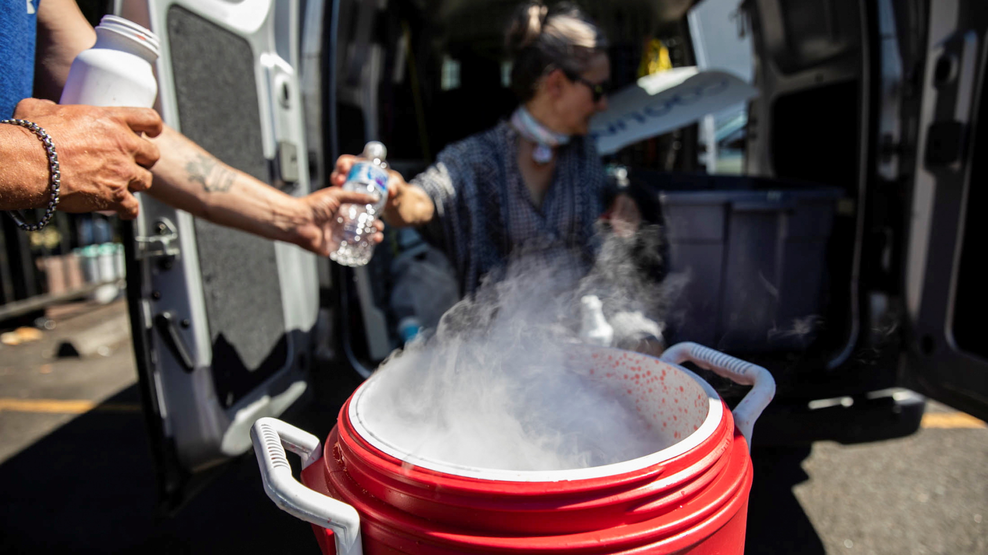 Nebel steigt aus einem Trockeneis-Behälter auf, in dem Leute Wasserflaschen kühlen. | REUTERS