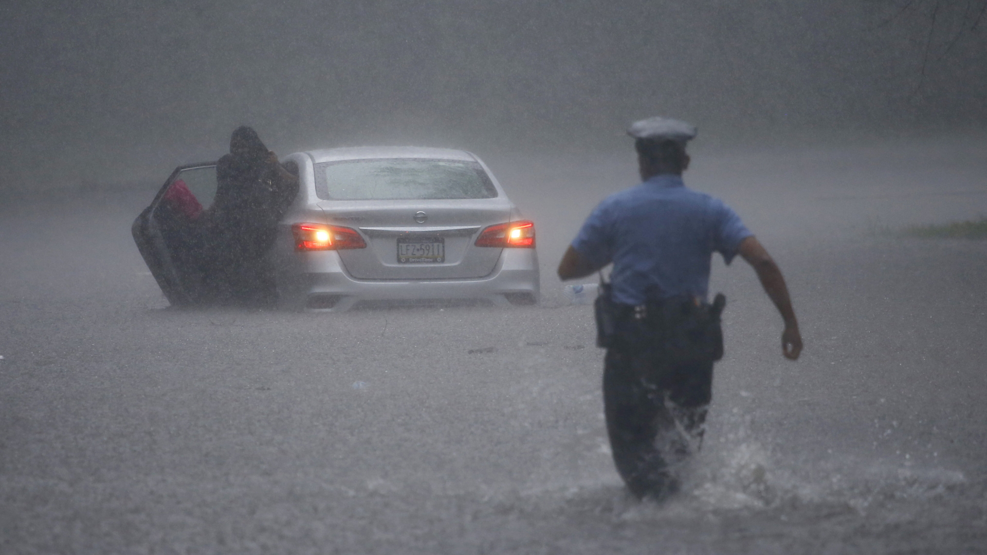 Ein Polizist in Philadelphia hilft einem auf einer überfluteten Straße gestrandeten Fahrer. | AP