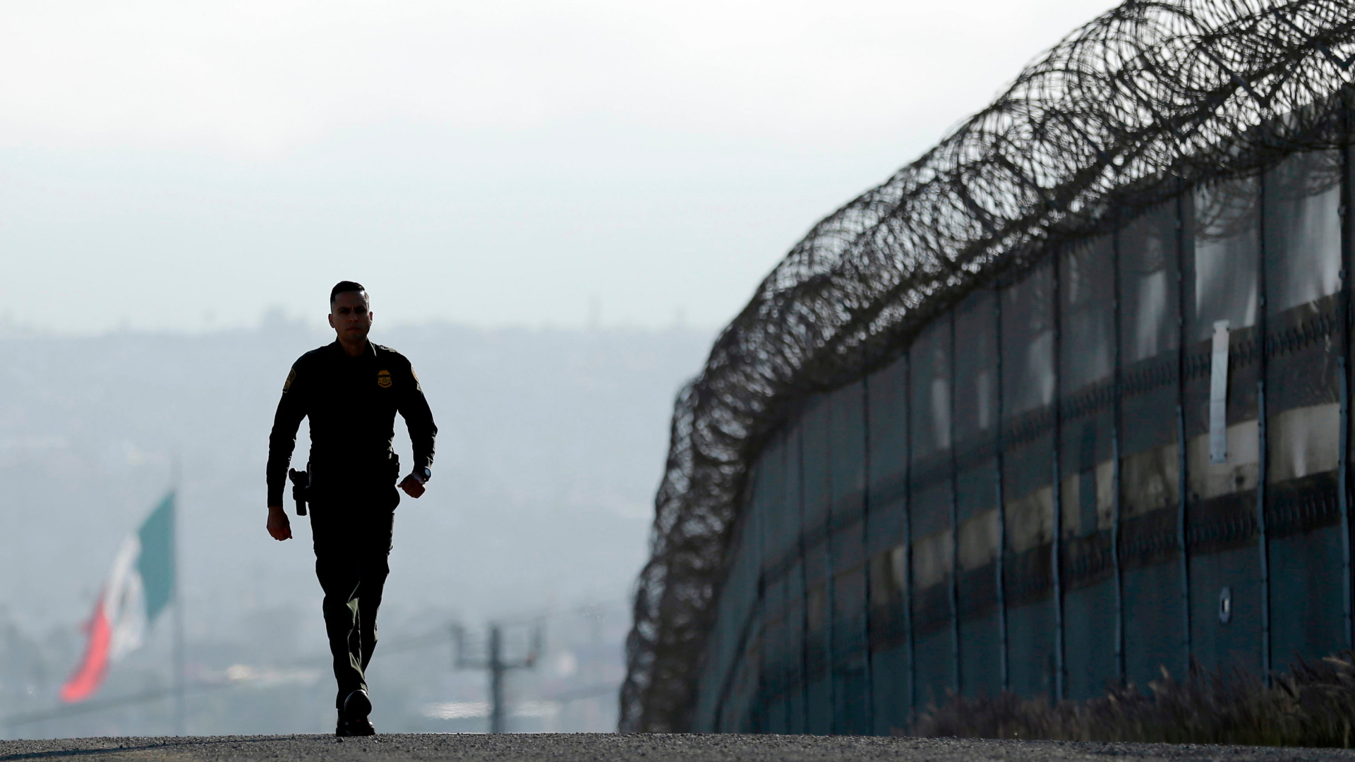 Ein Soldat läuft am Grenzzaun zwischen den USA und Mexiko entlang. | Bildquelle: AP