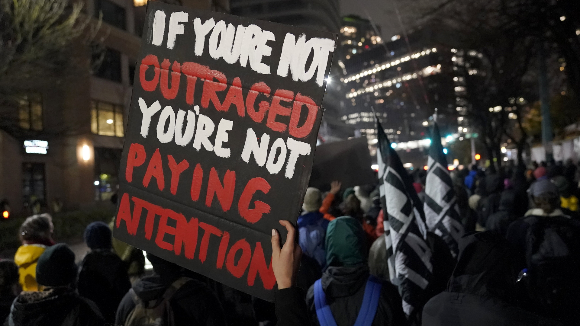 "Wer nicht empört ist, ist nicht informiert", steht frei übersetzt auf einem Protestplakat, dass Teilnehmer einer Demonstration in Seattle hochhalten. | AP
