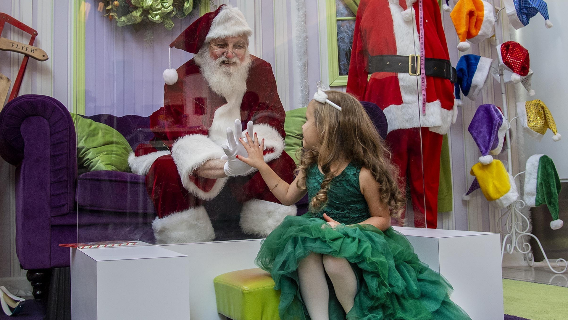 Ein Mädchen aus New Jersey legt ihre Hand an eine Plexiglasscheibe. Dahinter sitzt der Weihnachtsmann. | AP