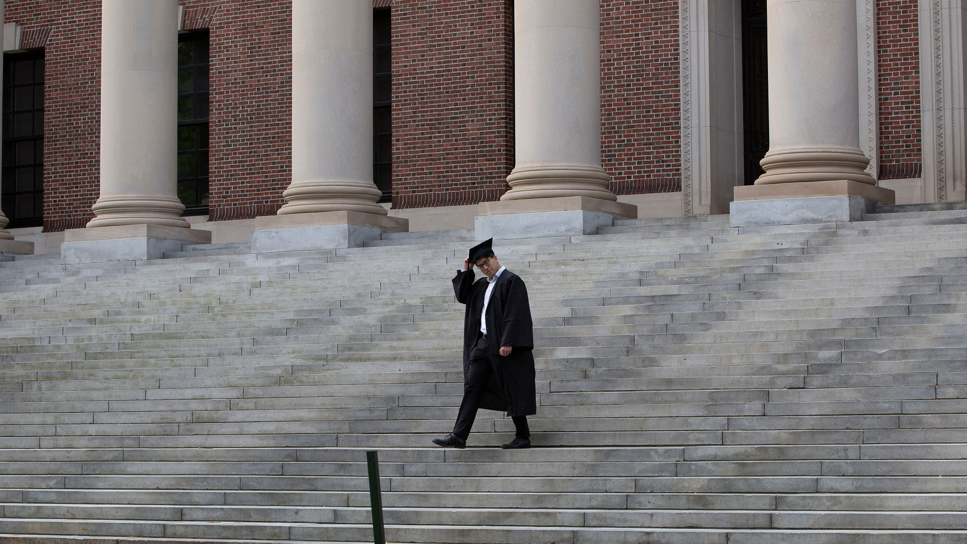 Ein Absolvent geht im schwarzen Talar die Stufen vor der Harvard Universität hinunter. | CJ GUNTHER/EPA-EFE/Shutterstock