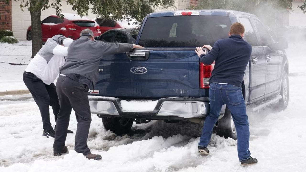 Ein Pick up ist im Schnee festgefahren - mit vereinten Kräften setzen ihn Leute im texanischen Round Rock wieder in die Spur. | AFP