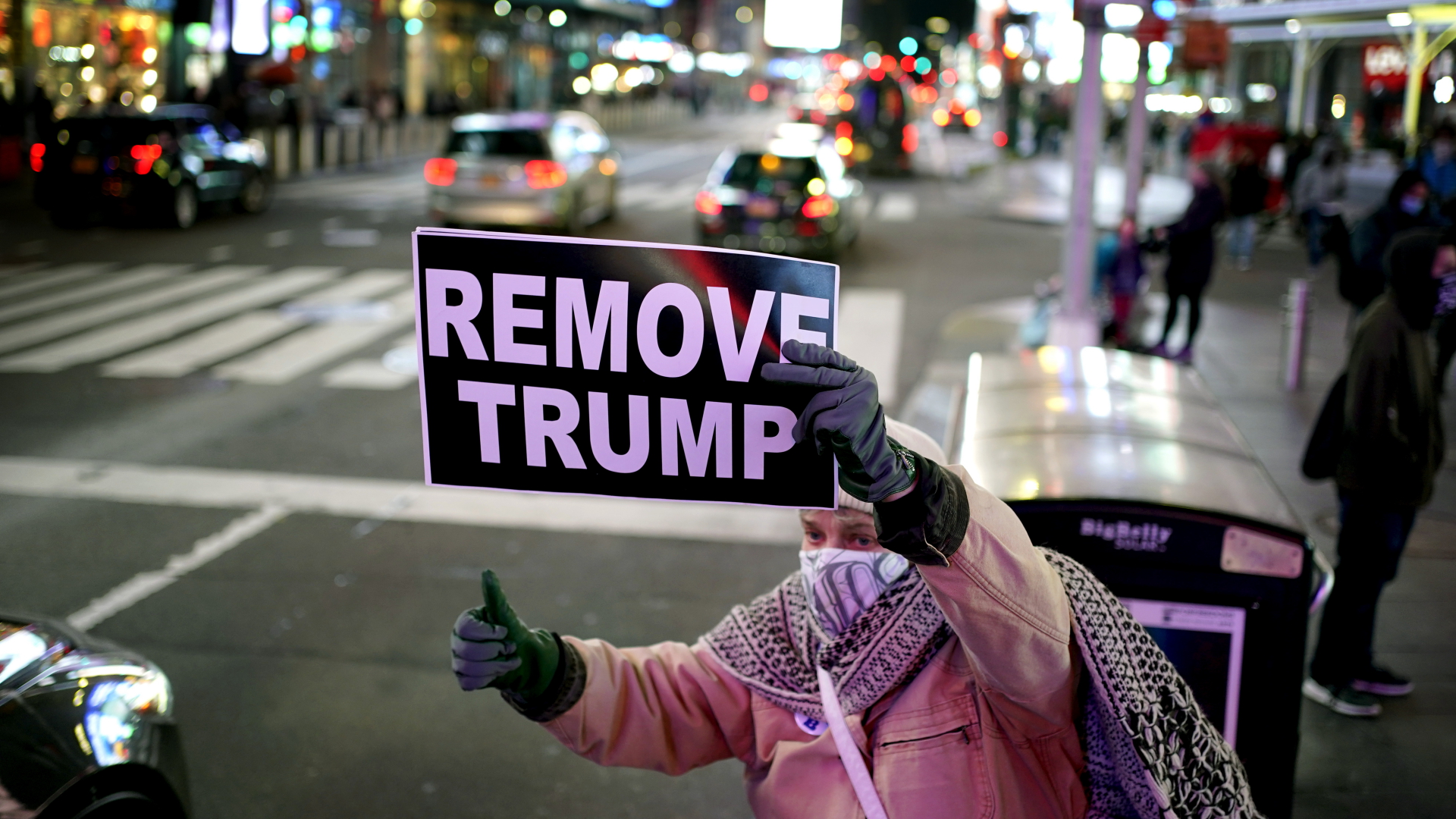 Eine Frau in New York hält ein Schild mit der Aufschrift "Remove Trump" ("Entfernt Trump") an einer Straße hoch. | dpa