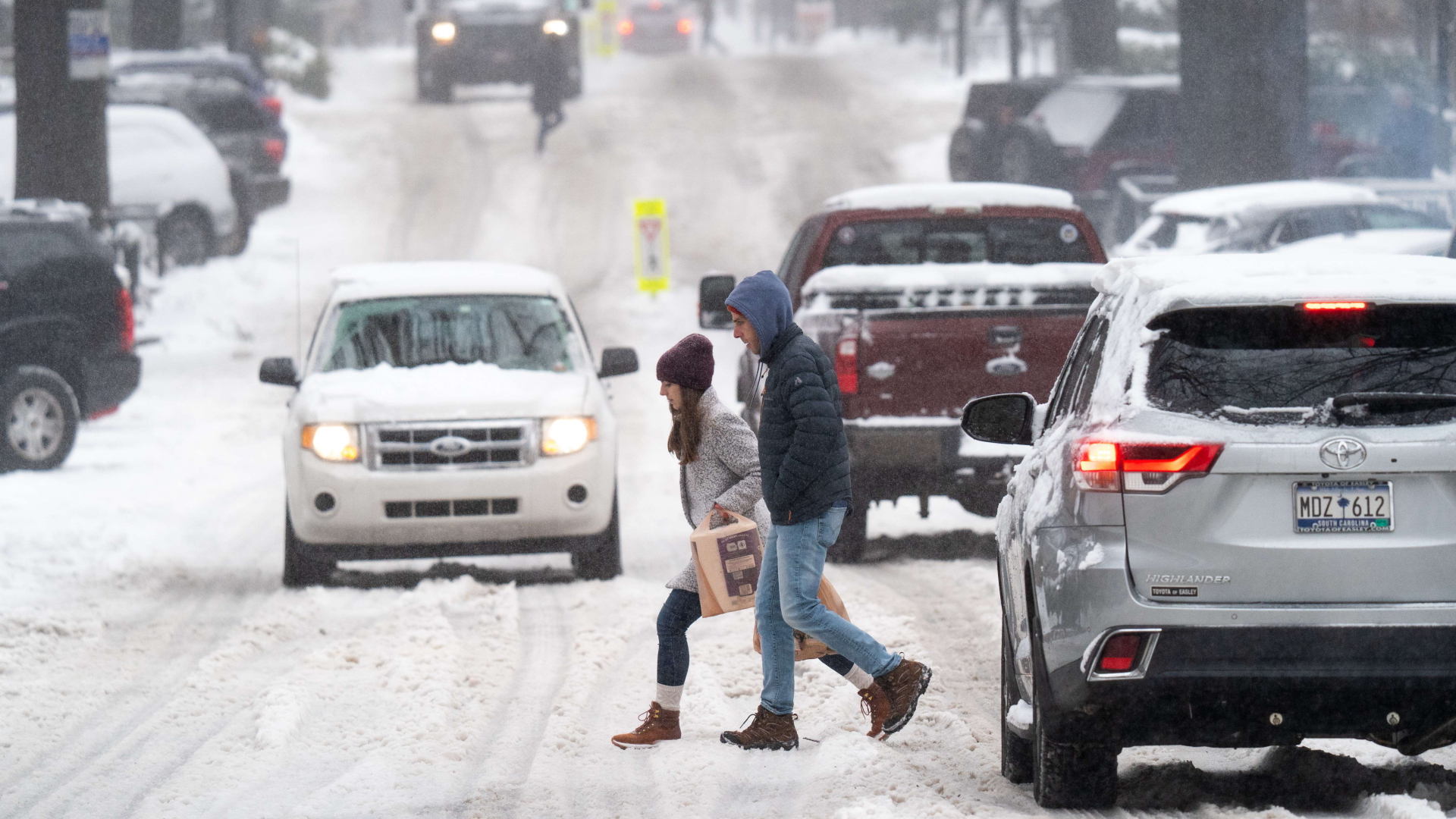 Fußgänger überqueren eine verschneite Straße im US-Bundesstaat South Carolina. | AFP
