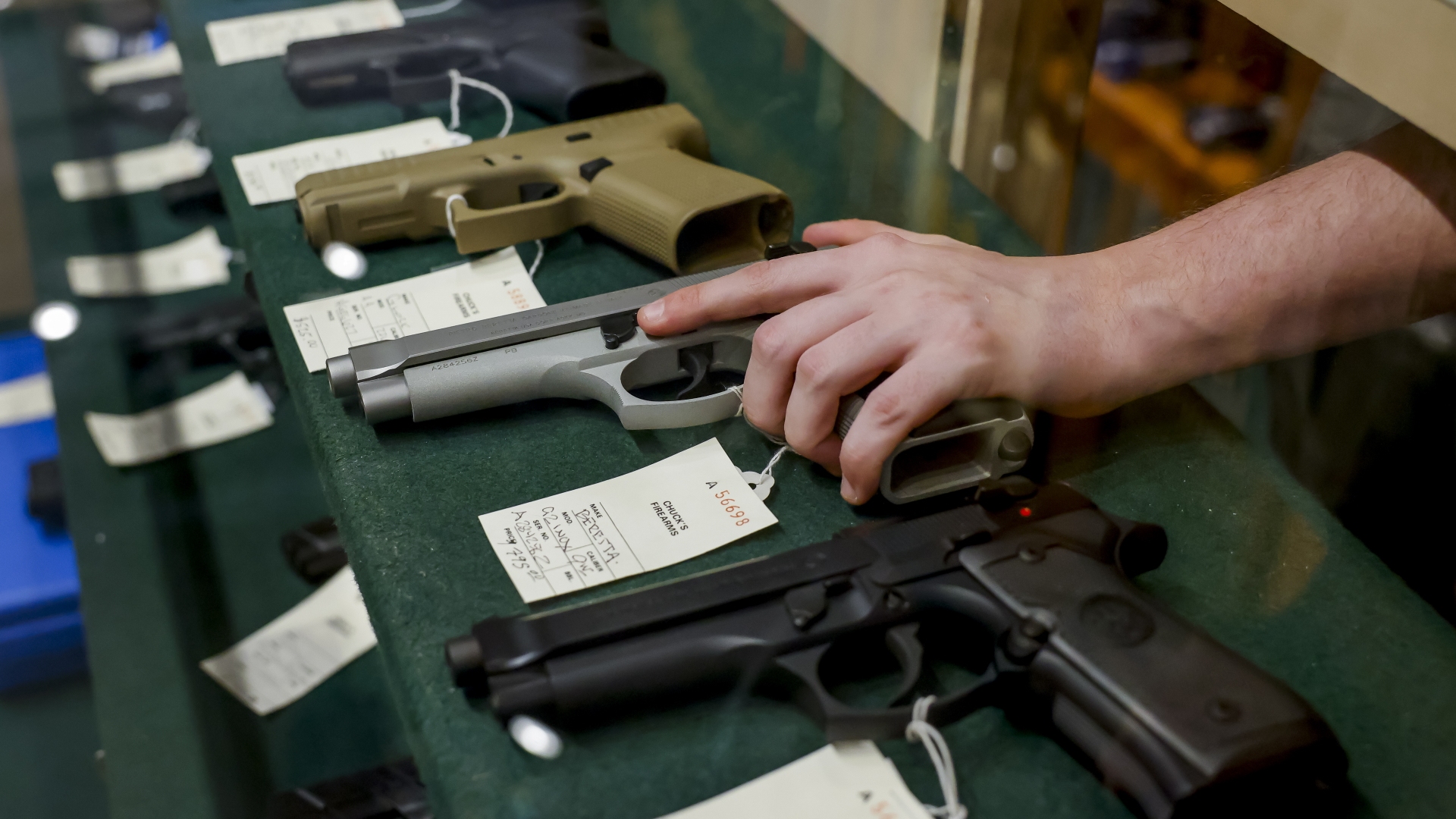 Eine Hand greift an einem Verkaufsstand auf einer Waffenmesse in New York nach einer Pistole. | EPA