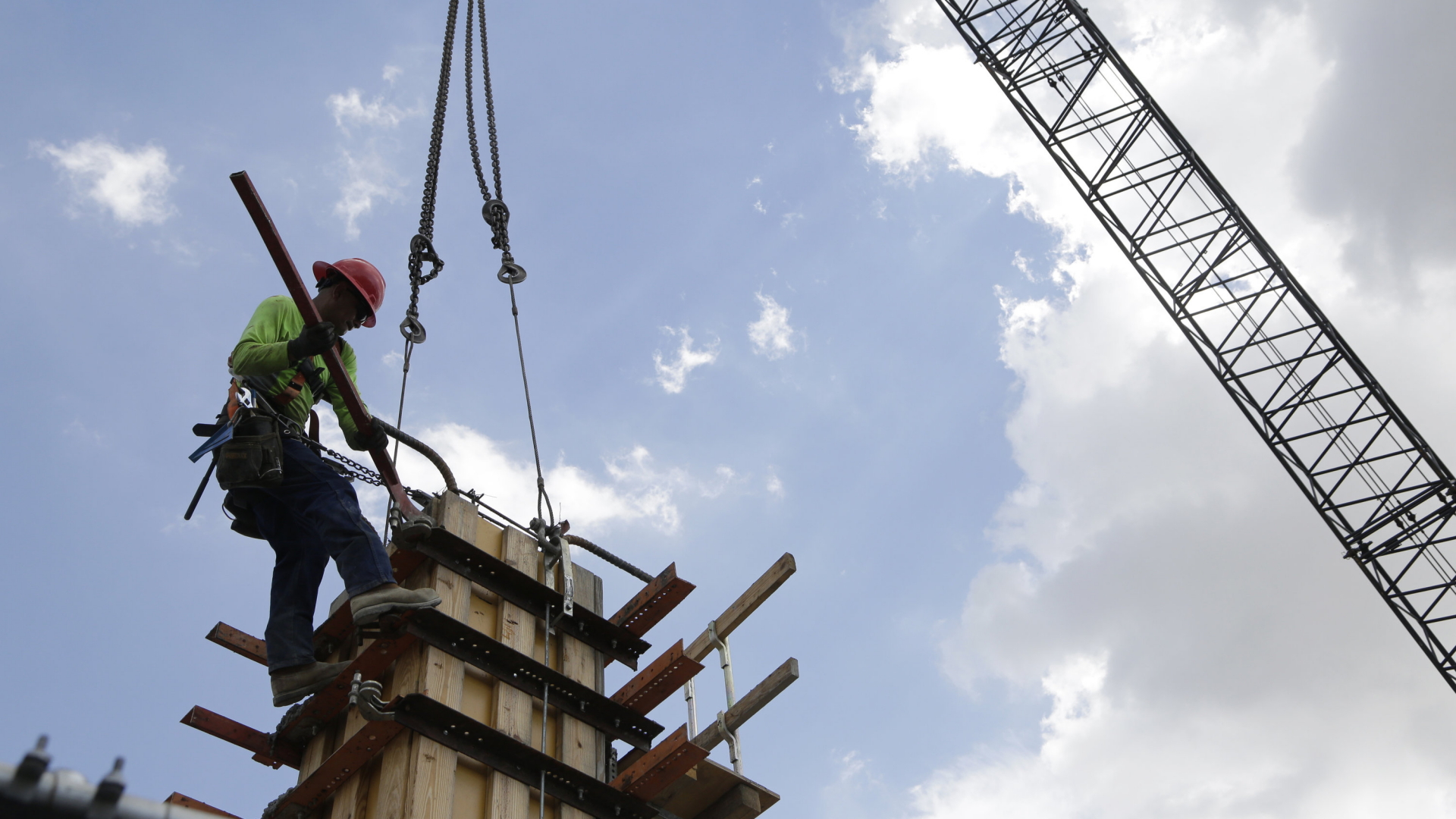 Ein Bauarbeiter löst eine Ladung von den Haken eines Krans. | AP