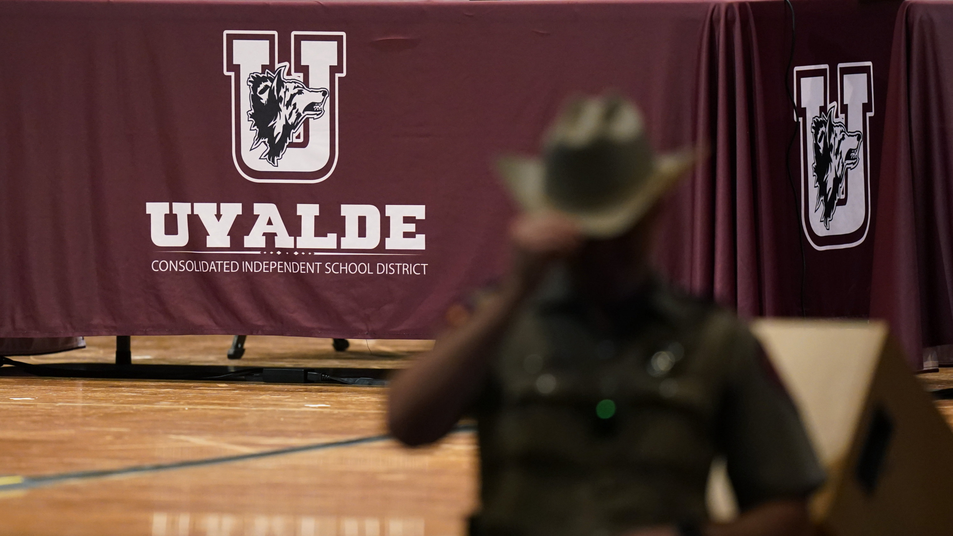 Ein Polizist steht vor dem Logo des Schulbezirks von Uvalde, Texas. | AP