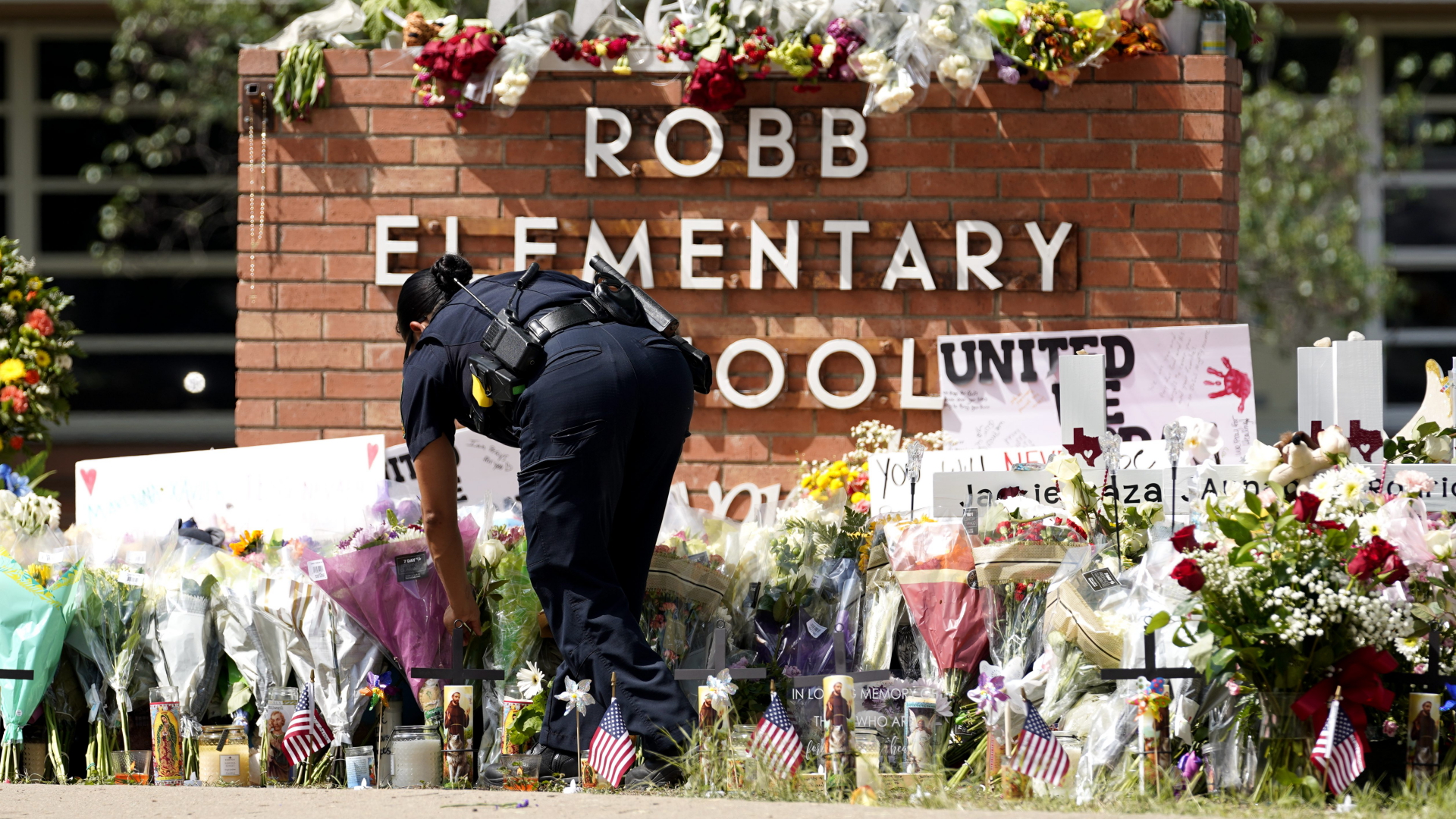 Eine Polizistin legt Blumen vor der Robb Elementary School nieder. | dpa