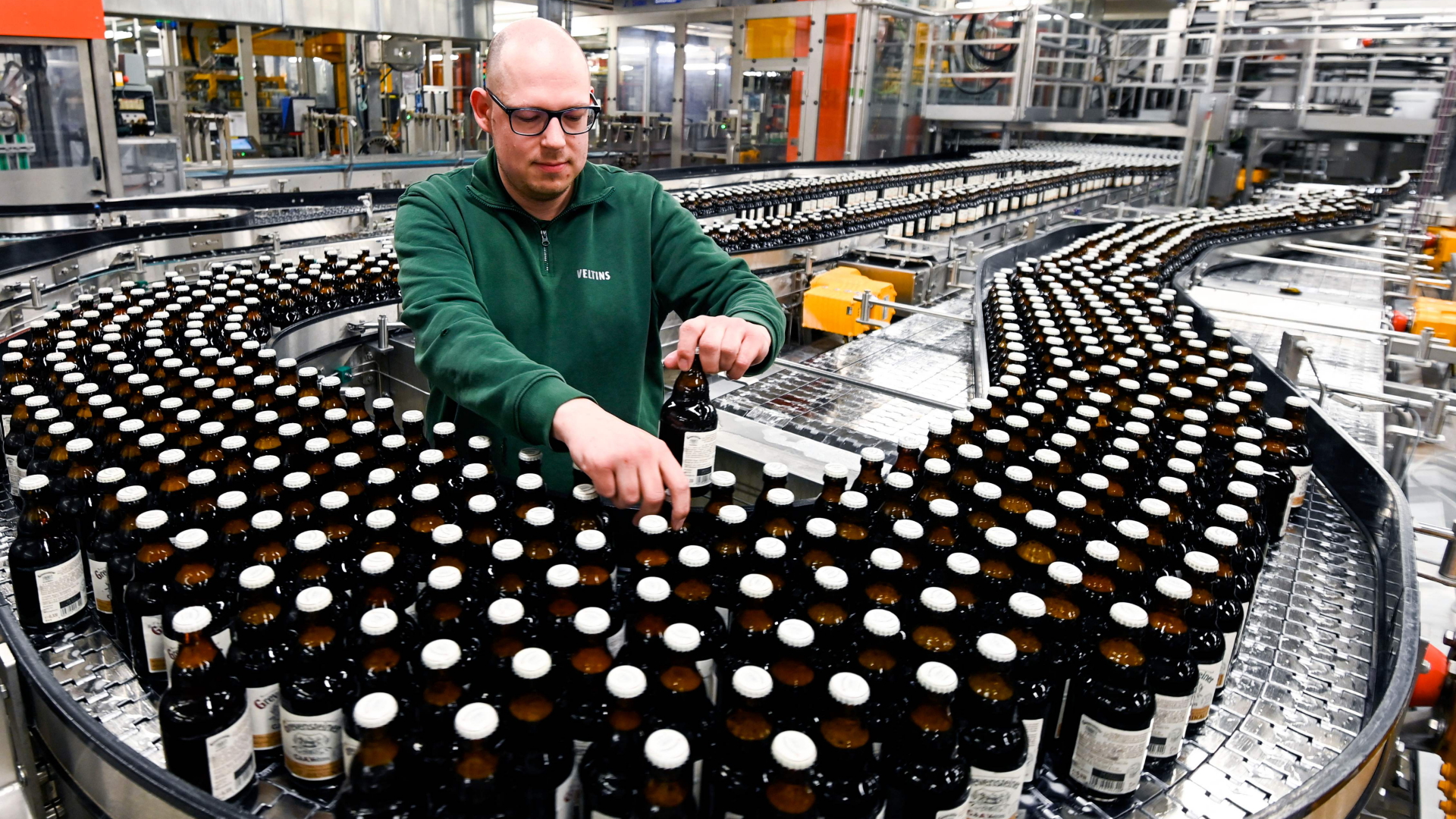 Ein Mitarbeiter prüft Bierflaschen auf einem Transportband der Veltins Brauerei in Grevenstein | AFP
