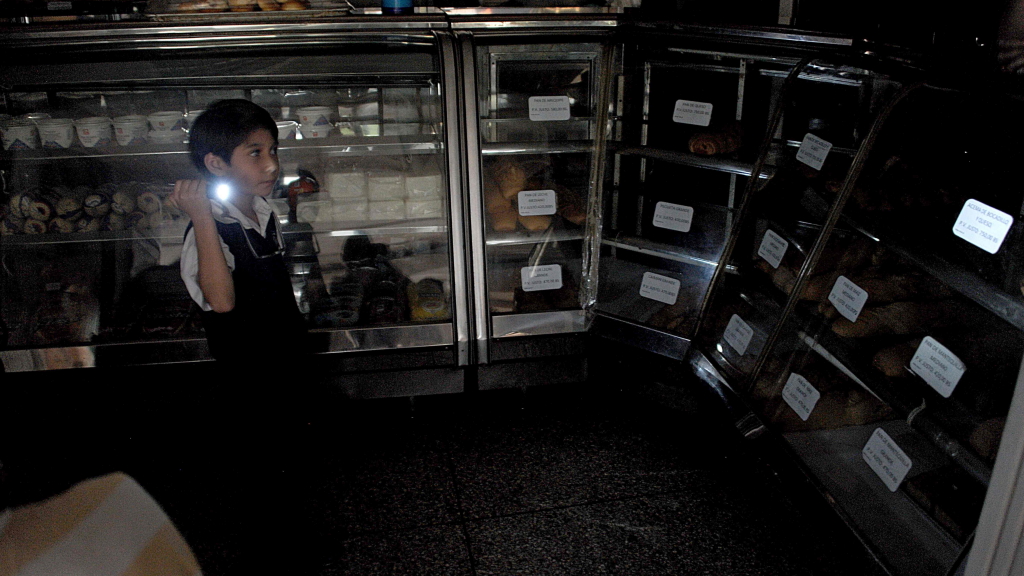Ein Junge läuft mit einer Taschenlampe durch einen dunklen Supermarkt. | null