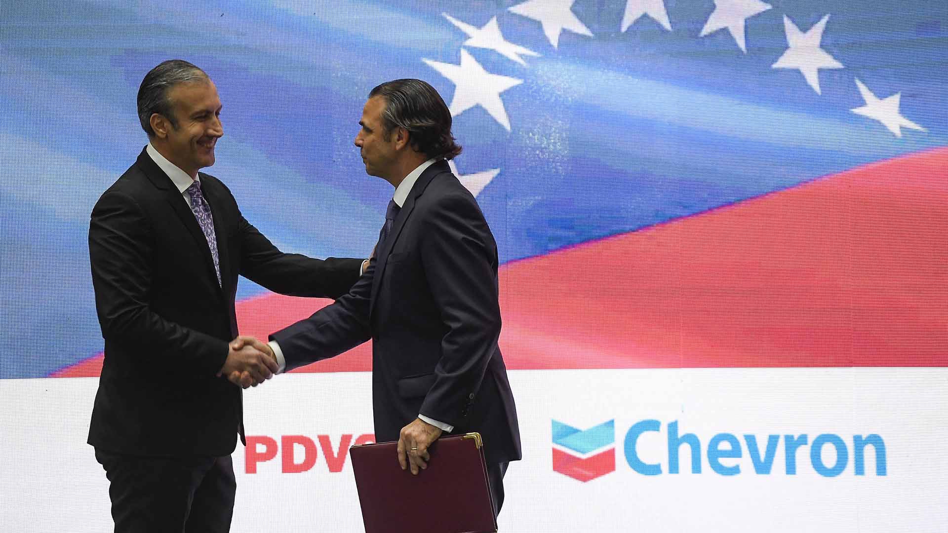 Venezuelas Ölminister El Aissami und der Präsident des amerikanischen Ölkonzerns Chevron in Venezuela, La Rosa, schütteln sich die Hände. | picture alliance/dpa/AP