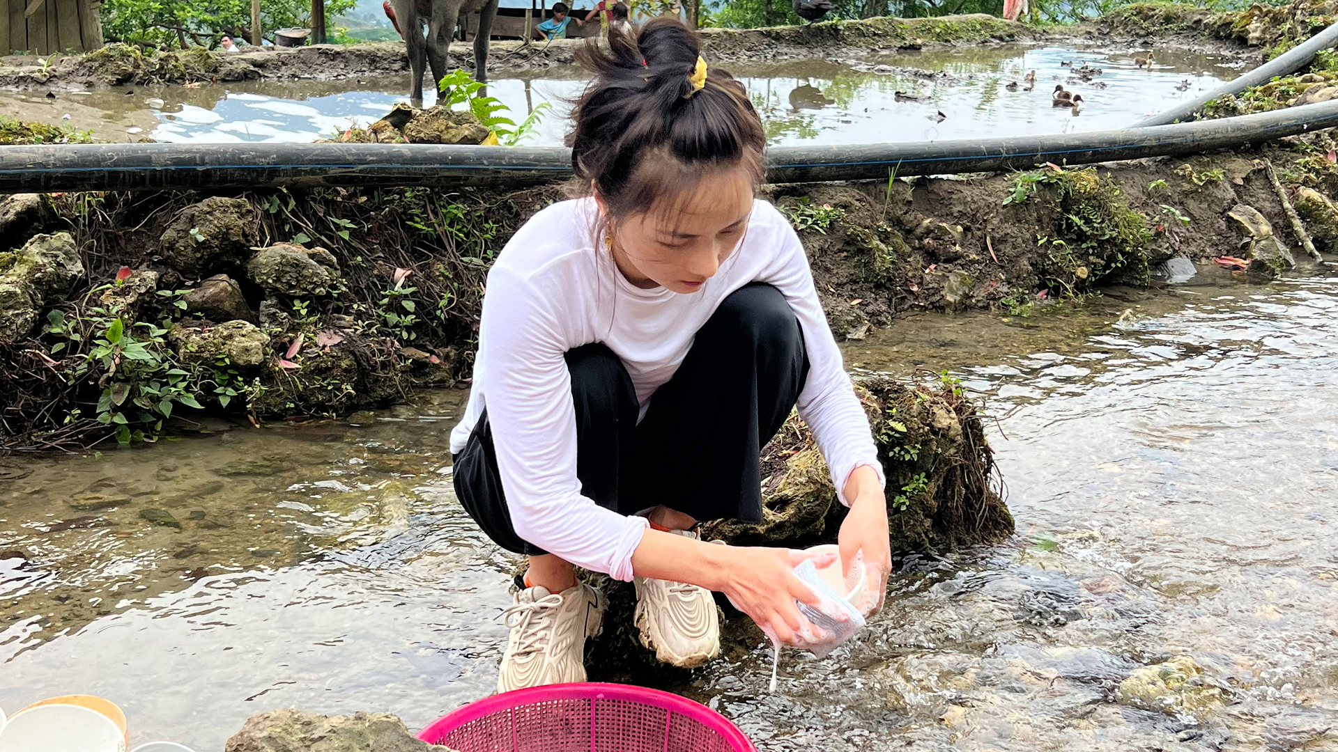 Lan wäscht Reisschüsseln in einem Fluss ab. | ARD-Studio Singapur