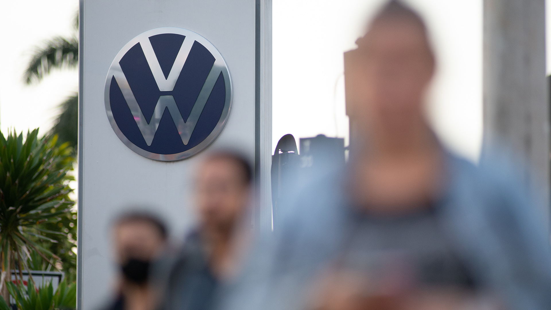  Passanten gehen an einem Schild des Autobauers Volkswagen (VW) in Brasilien vorbei. | picture alliance/dpa