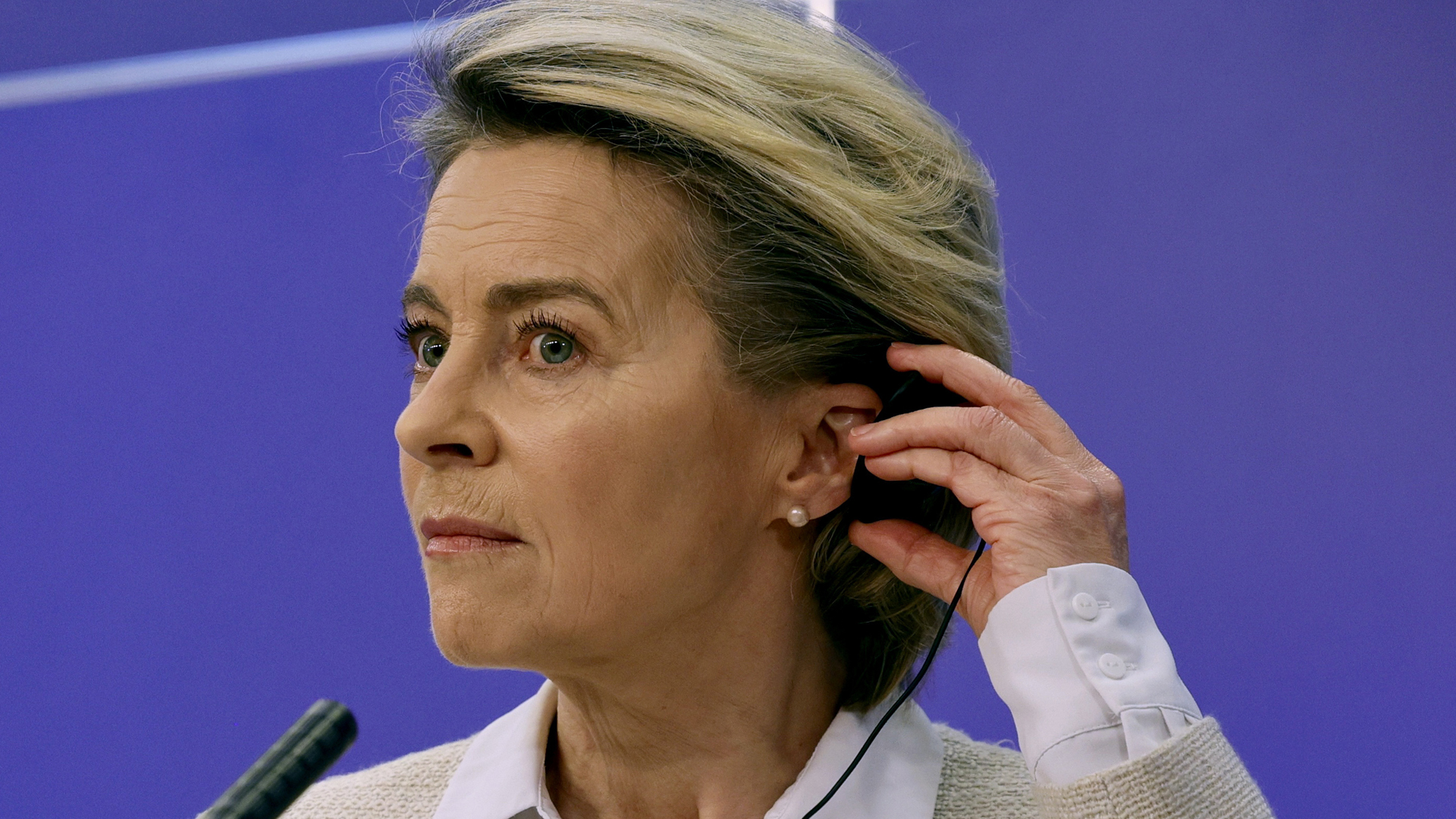 Ursula von der Leyen hält einen In-Ohr-Kopfhörer vom Kopf weg. | picture alliance / ASSOCIATED PR