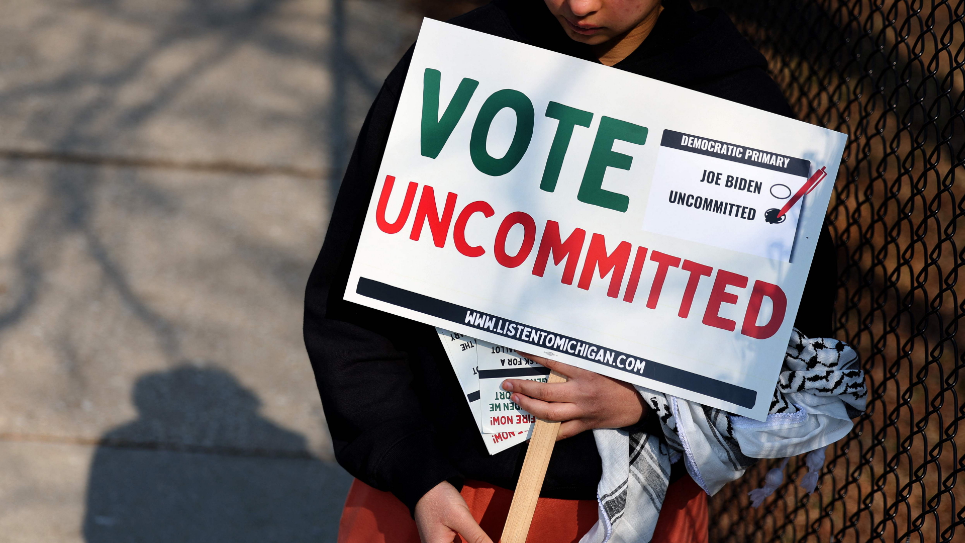 Eine Frau hält ein Schild vor einem Wahllokal in Dearborn, Michigan, hoch, auf dem dafür geworben wird "uncommited" zu stimmen.