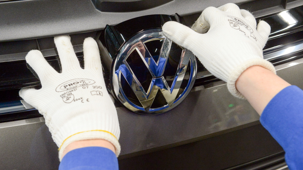 Ein Arbeiter bringt das VW-Logo an einem Kühlergrill an. (Archivbild)