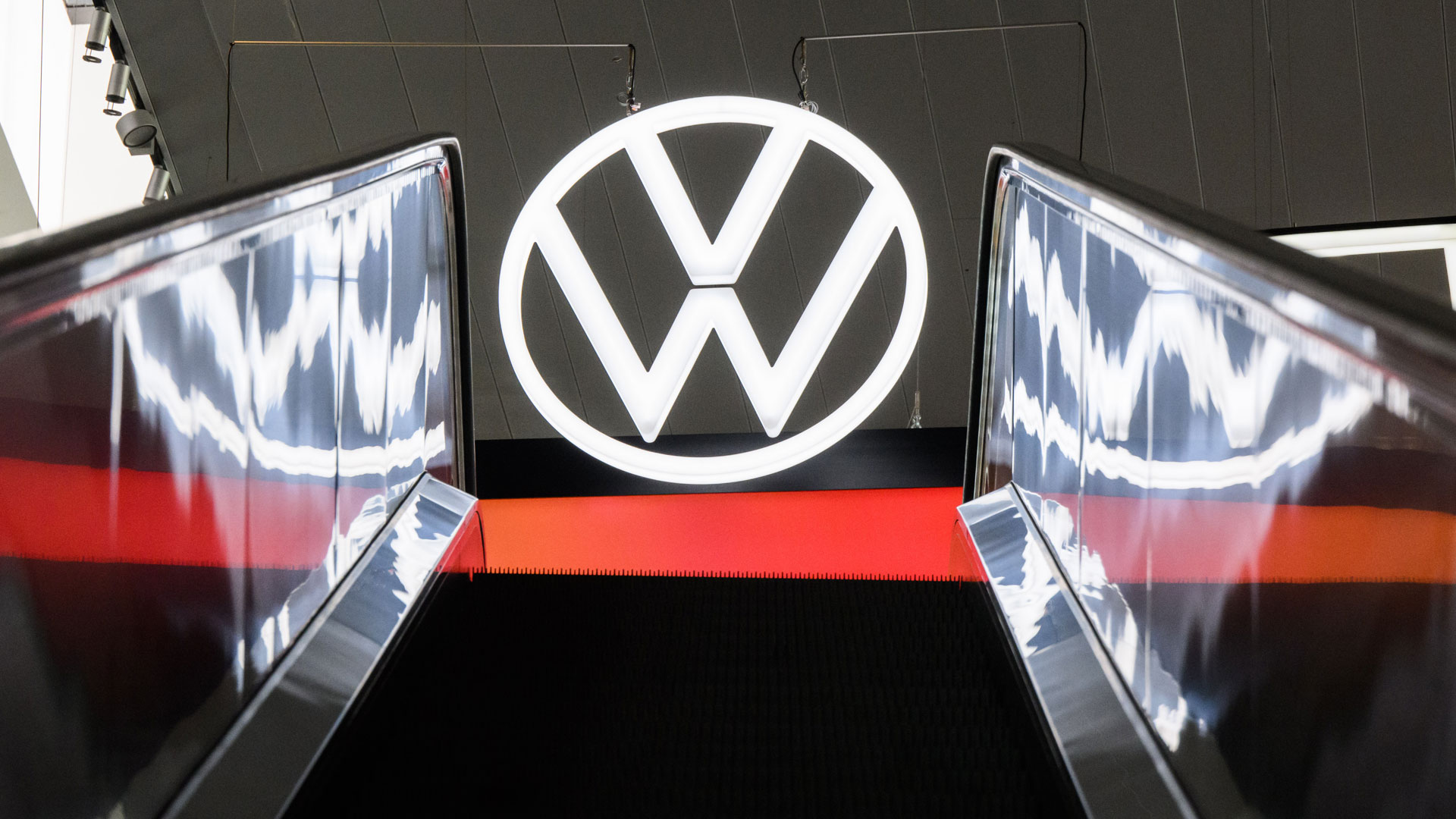 Ein Volkswagen Logo spiegelt sich in einer Rolltreppe in der Autostadt am Volkswagen Stammwerk. | picture alliance/dpa