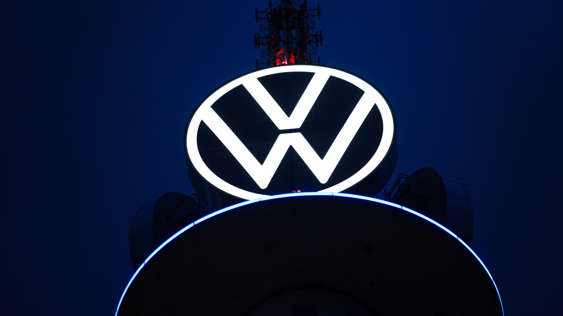 Das Volkswagen-Logo leuchtet auf dem VW-Tower in Hannover vor dunklem Himmel. | dpa