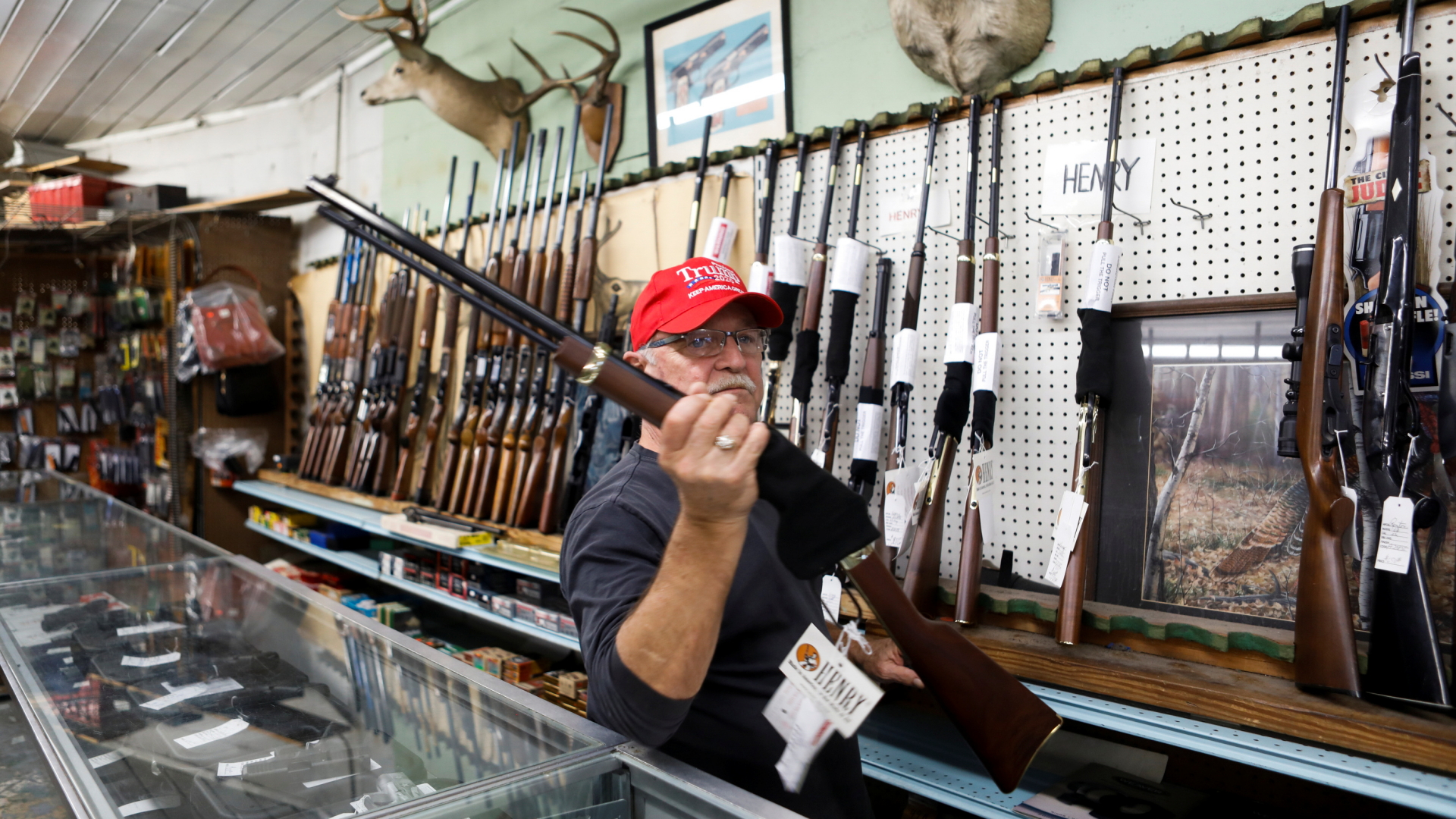 In einem US-amerikanischen Waffengeschäft hält ein Verkäufer mit Trump-Mütze ein Gewehr in die Höhe. | REUTERS