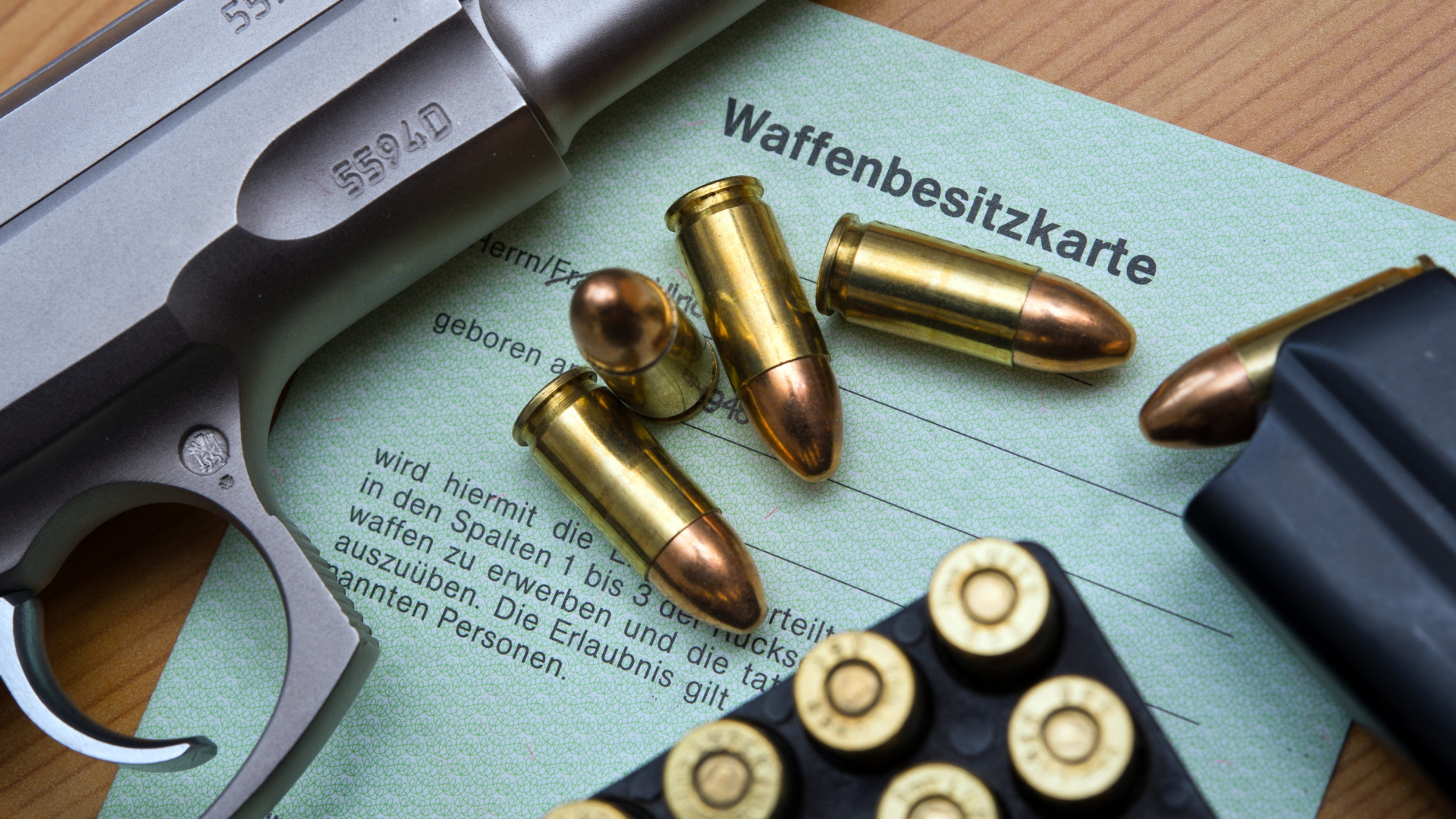 Eine Kaliber 9 mm Pistole, Patronen und ein Magazin liegen auf einer Waffenbesitzkarte. | Bildquelle: dpa