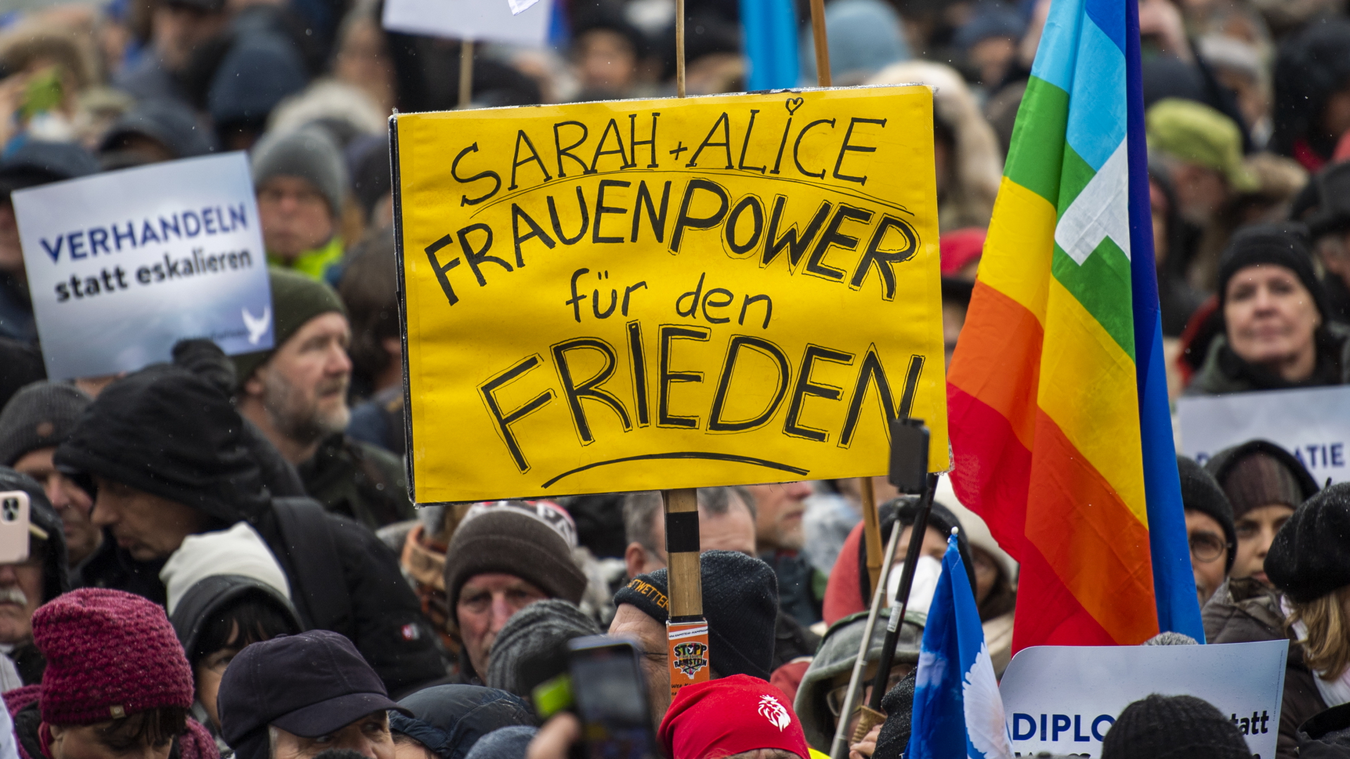 Ein Teilnehmer einer Demonstration für Verhandlungen mit Russland am Brandenburger Tor hält ein Plakat mit der Aufschrift "Sarah + Alice - Frauenpower für den Frieden" | dpa