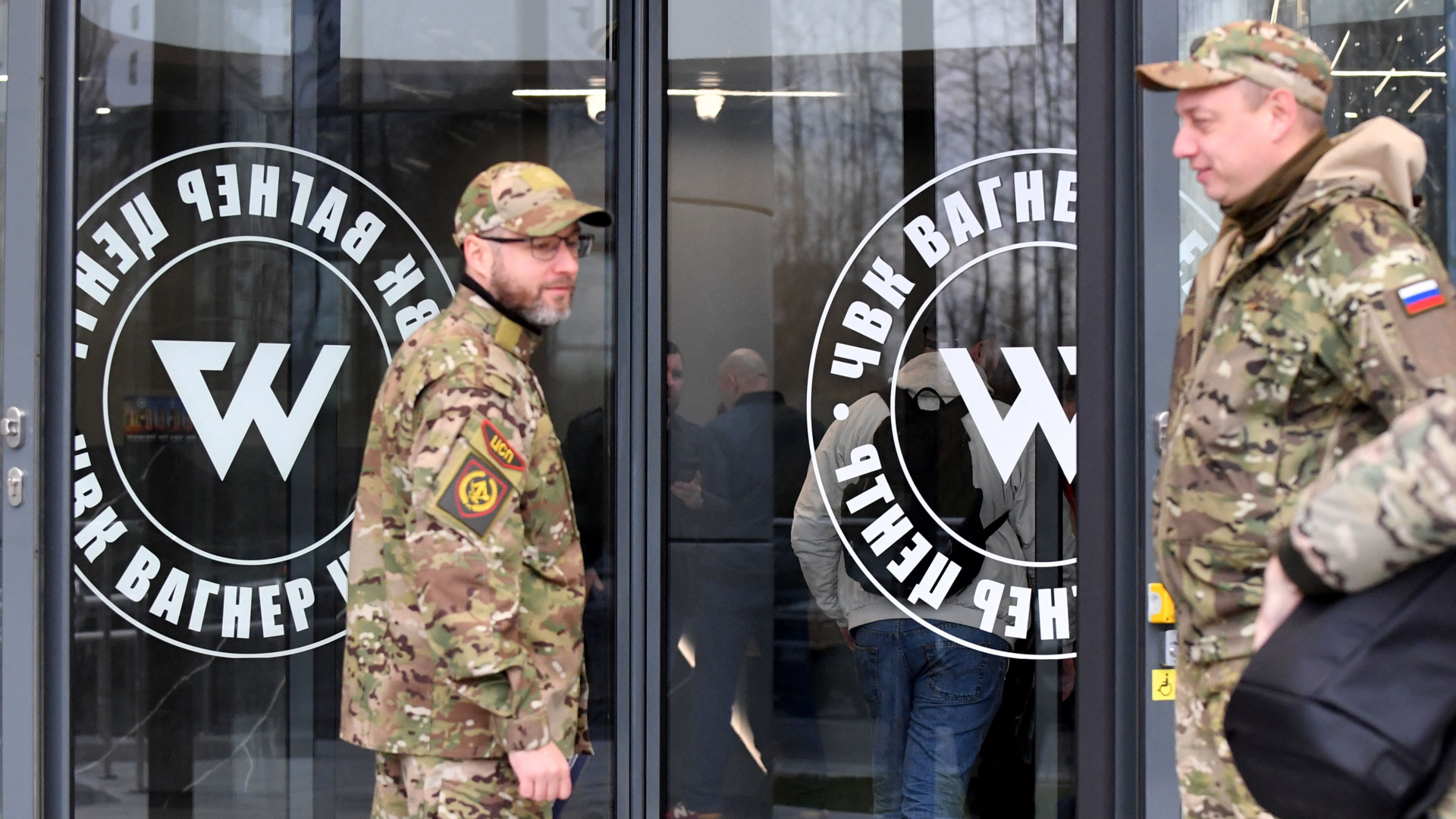 Zwei Männer in Camouflage vor dem "PMC Wagner Centre" der Wagner-Gruppe. | AFP