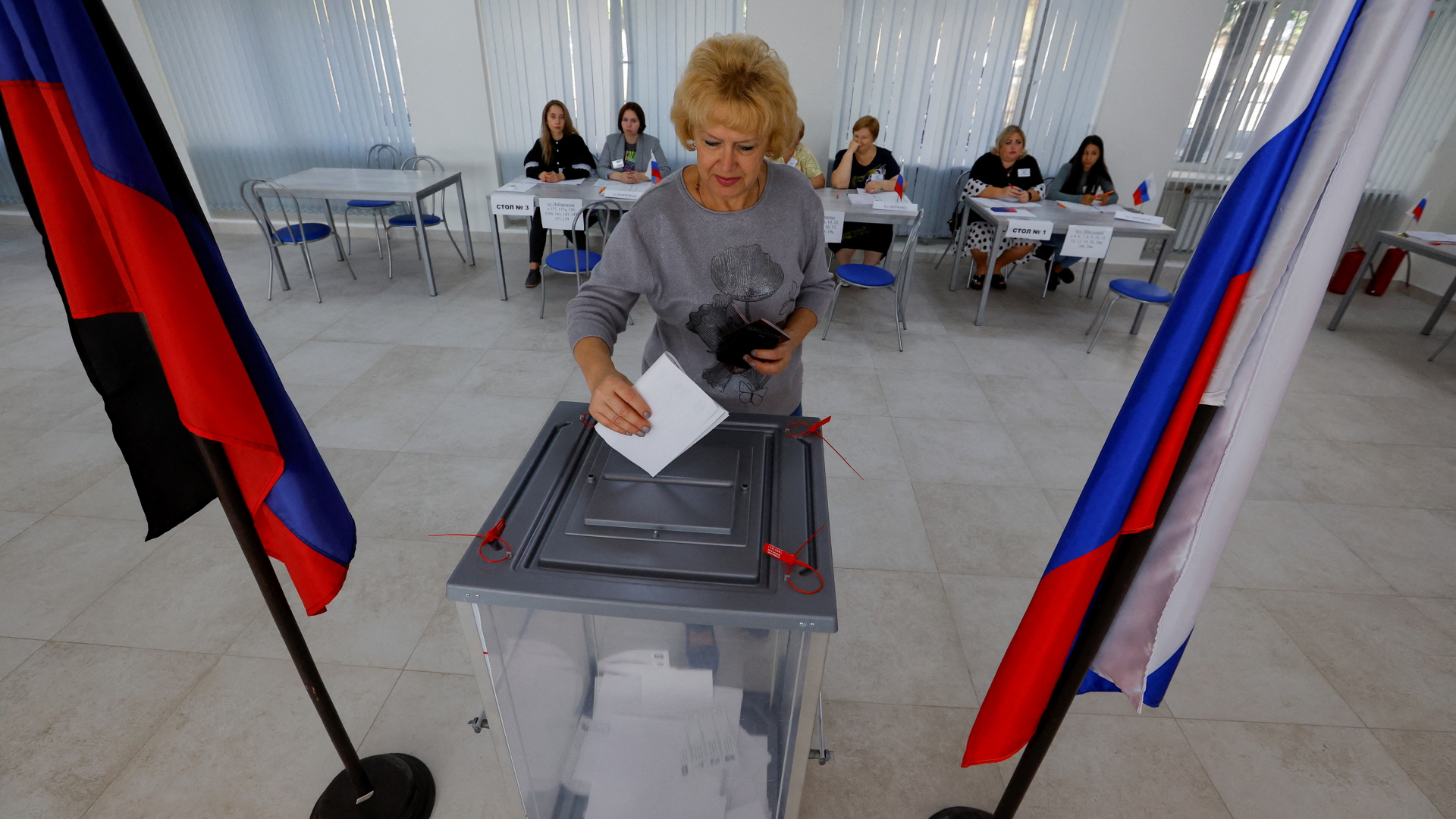 Eine Frau wirft in der von Russland besetzten Region Donezk einen Wahlzettel in eine Urne.