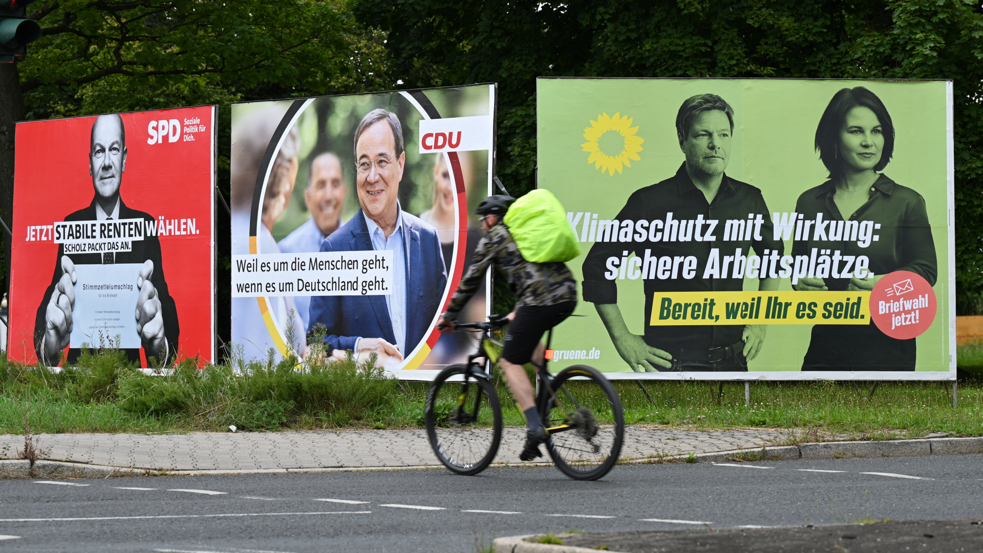 Ein Radfahrer fährt an großen Wahlplakaten mit den Spitzenkandidaten | dpa