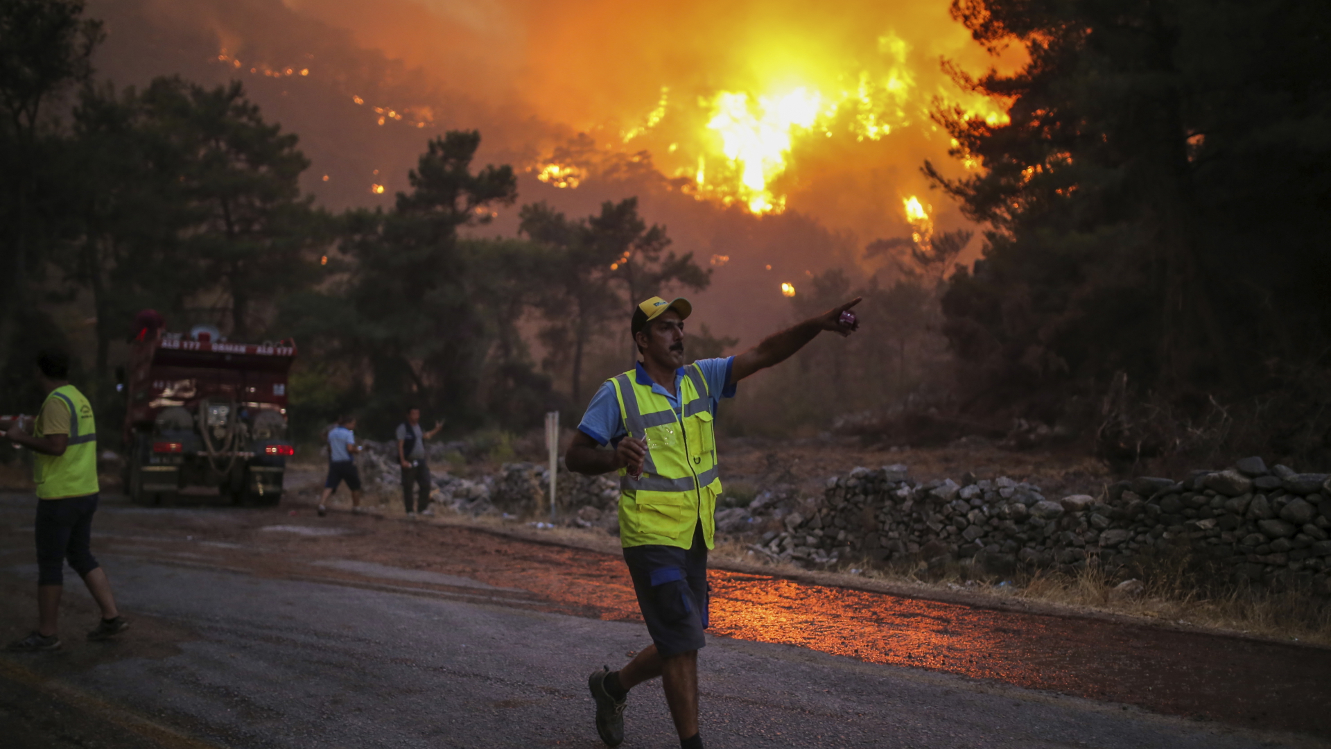 Ein Feuerwehrmann zeigt auf ein Feuer, das im Dorf Cokertme in der Nähe von Bodrum in der Türkei wütet. | dpa