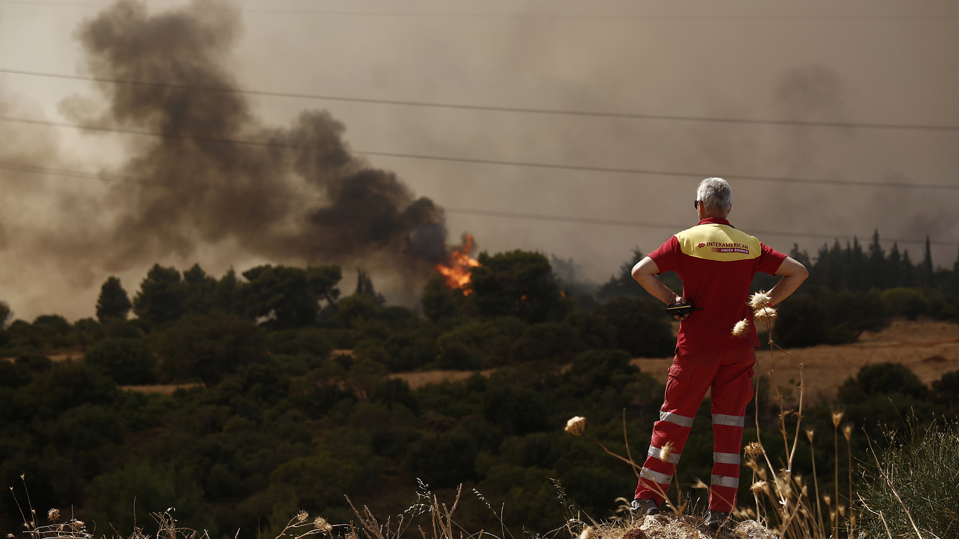 Ein Mann blickt auf einen Waldbrand bei Varympompi. | EPA