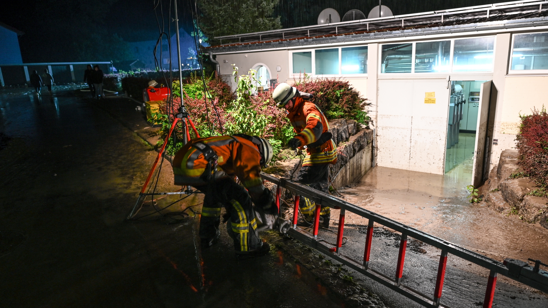 Feuerwehrmänner verlegen in Wangen im Allgäu einen Schlauch, um einen Keller auszupumpen, der beim Hochwasser vollgelaufen ist.  | dpa