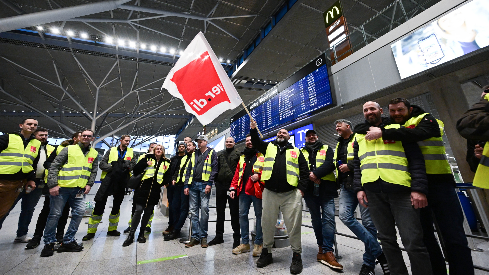 Streikende Mitarbeiter des Flughafens Stuttgart stehen mit Westen der Gewerkschaft Verdi in der leeren Abflughalle auf dem Flughafen Stuttgart | dpa