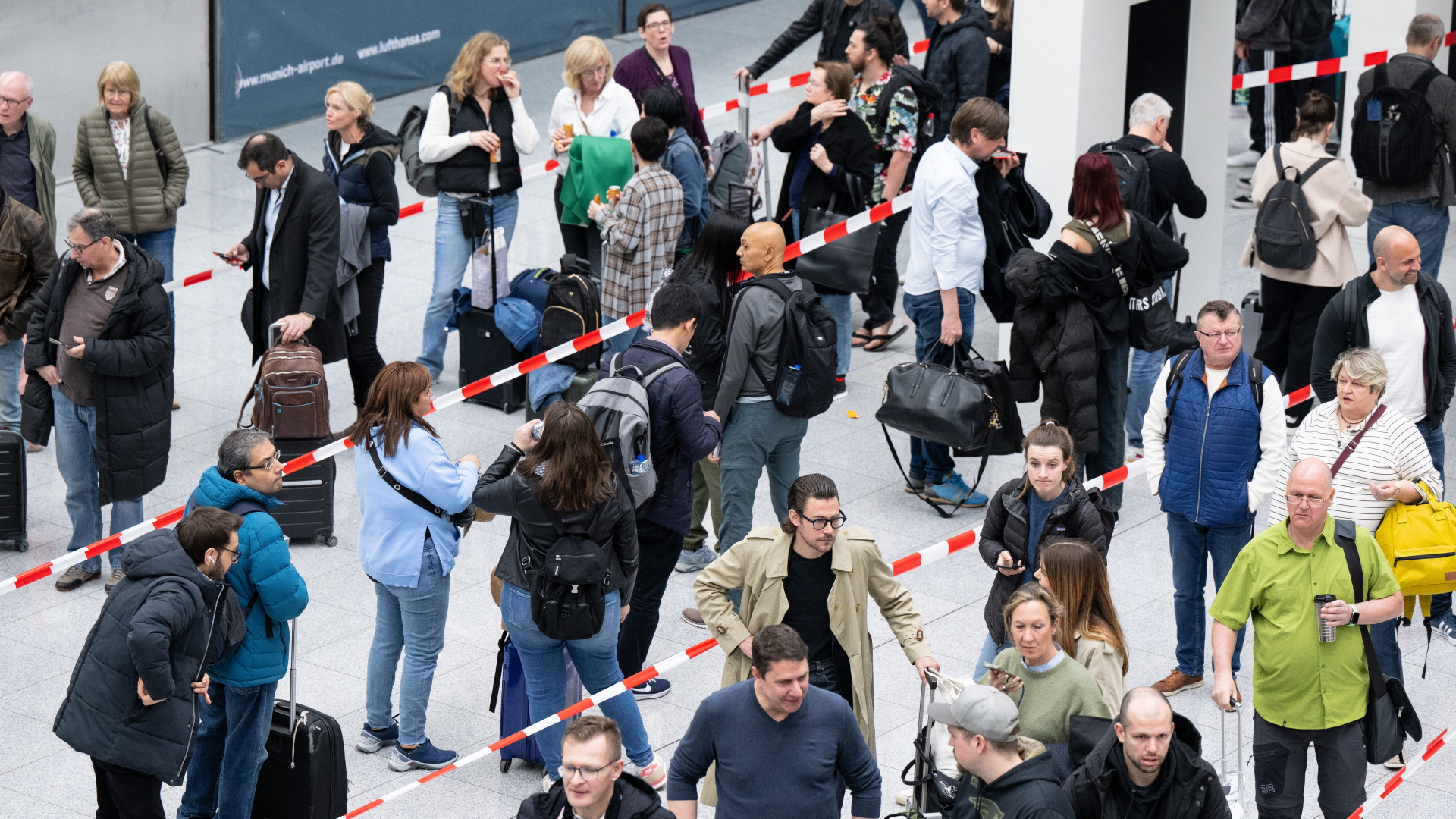 Passagiere gehen am Terminal des Flughafens München zur Sicherheitskontrolle.