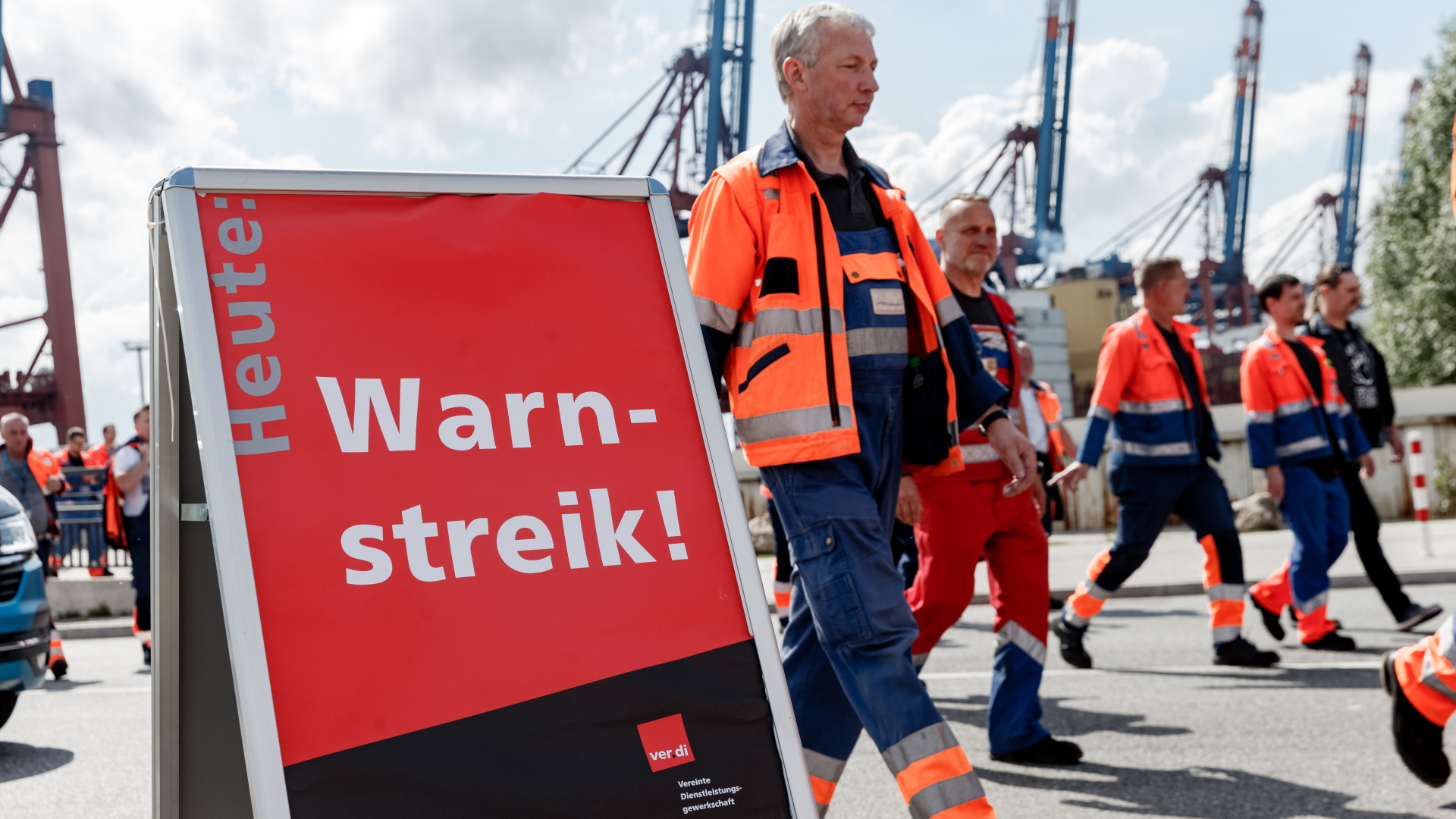Arbeiter im Hamburger Hafen gehen mit einem Streikschild zu einer Streikversammlung (Archivbild) | dpa