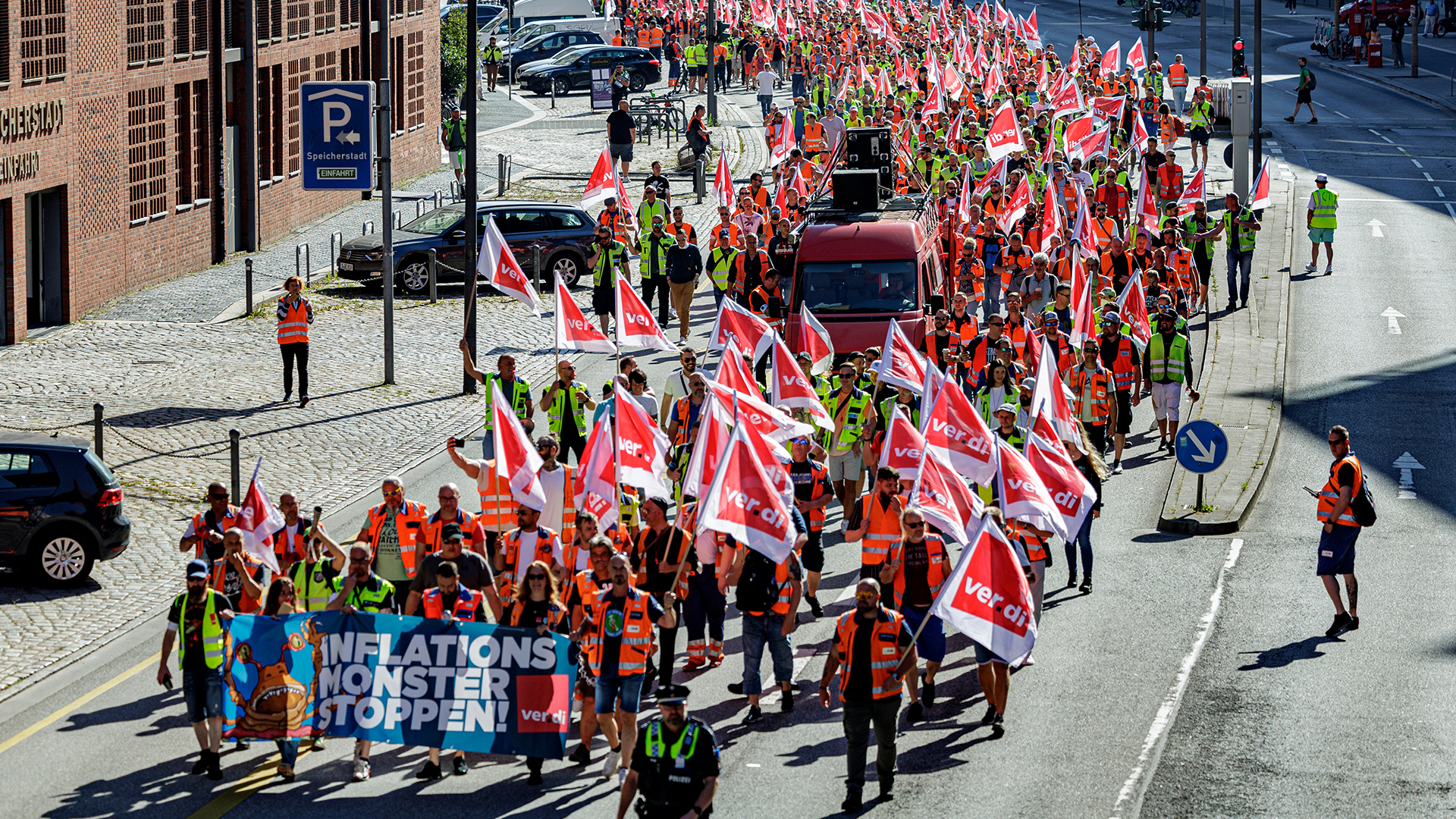 Streikende Hafenarbeiterinnen und -arbeiter mit Ver.di-Flaggen auf einer Straße in Hamburg. | dpa