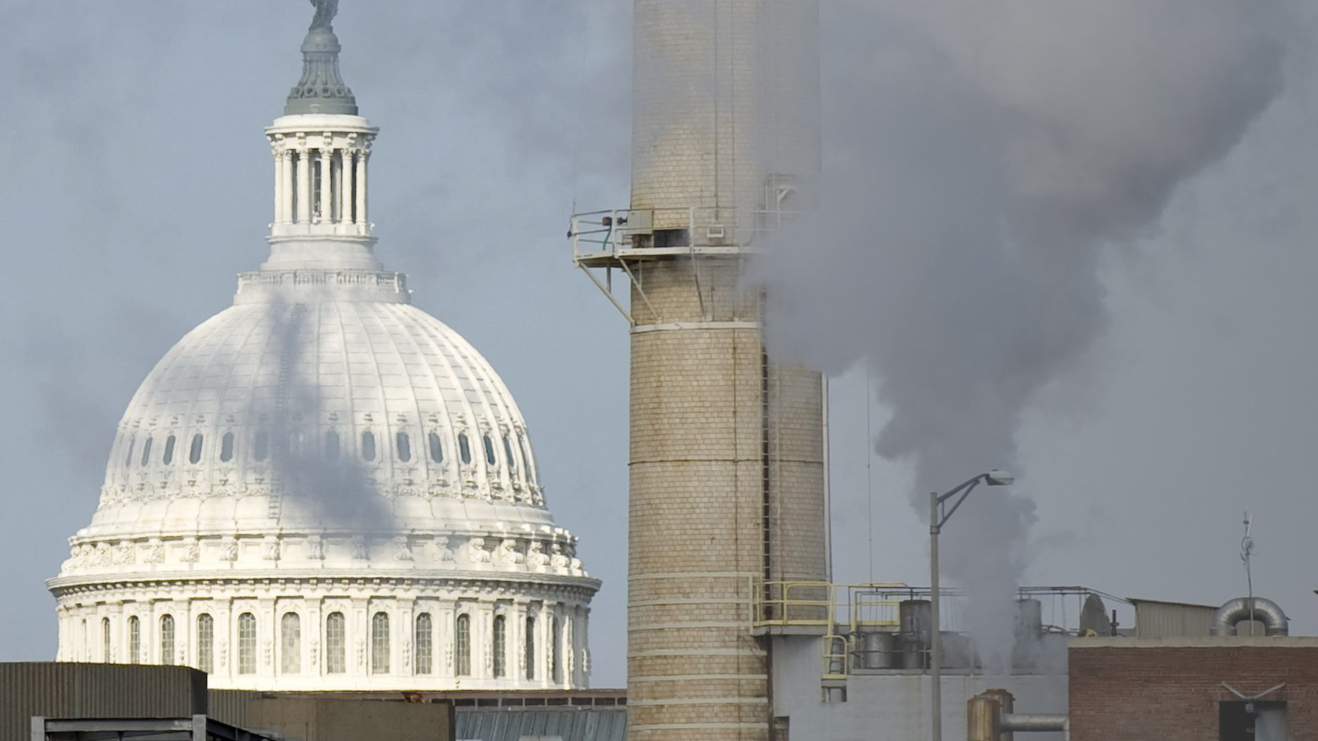 Der Rauch eines Kohlekraftwerkes kommt vor der Kulisse des Capitol in Washington (USA) aus einem Schornstein.  | picture alliance / dpa