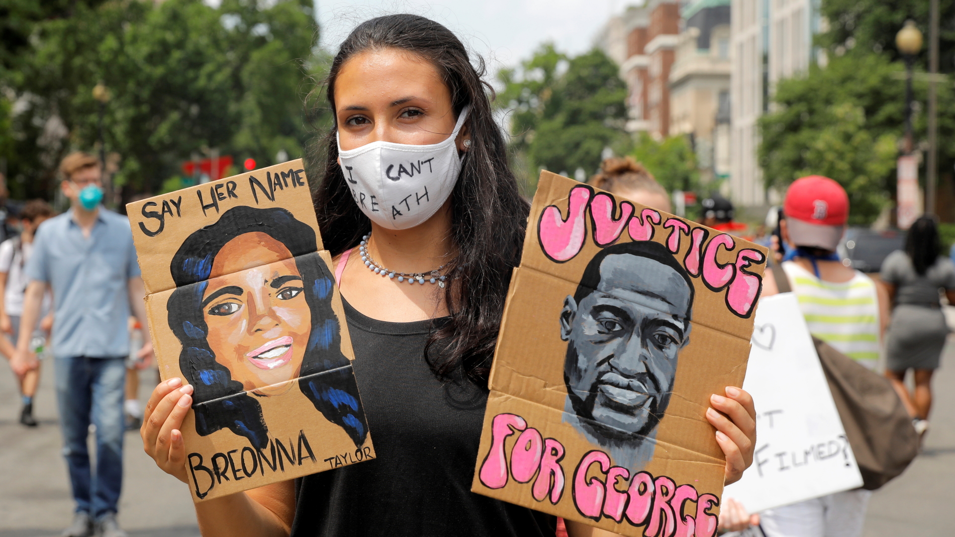 Eine Teilnehmerin der Proteste in Washington, D.C. hält Schilder mit den Gesichtern und Namen von Breonna Taylor und George Floyd hoch, die durch rassistische Gewalt starben. | REUTERS