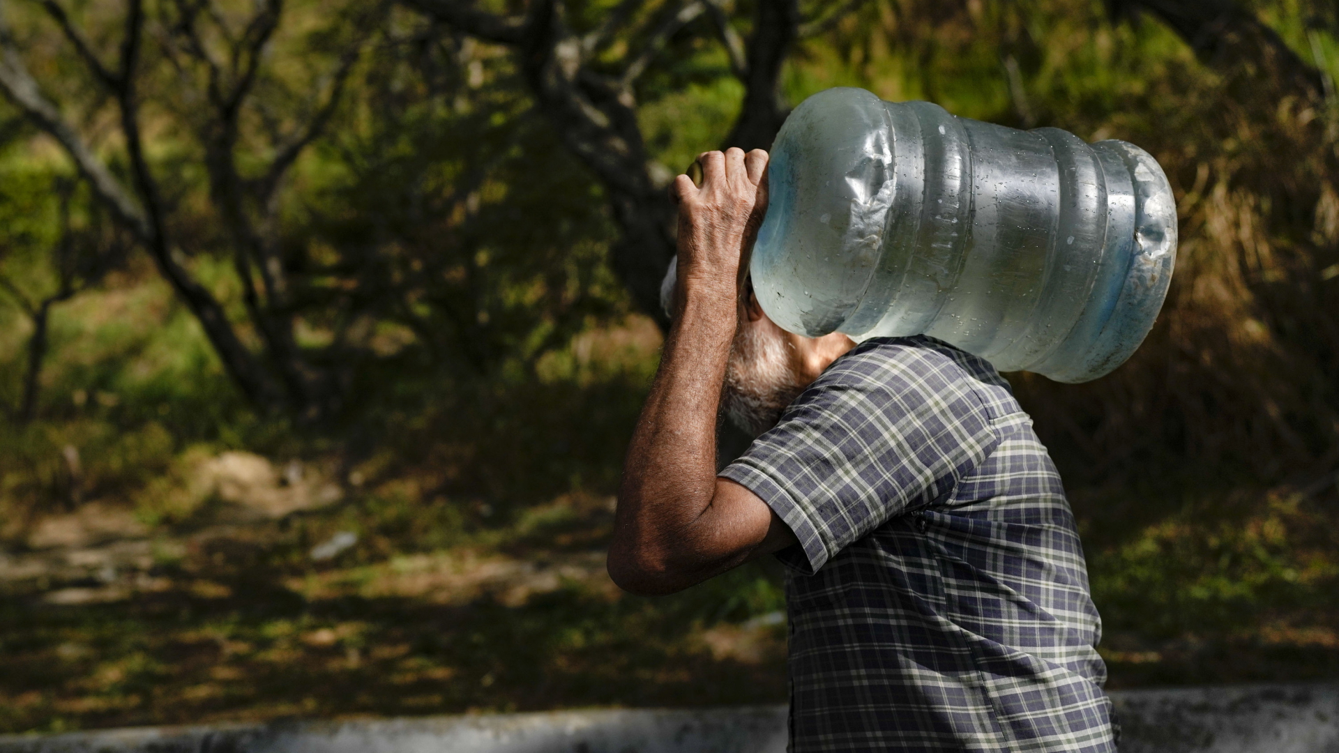 Ein Mann trägt in Venezuela einen Wasserkanister. | AP