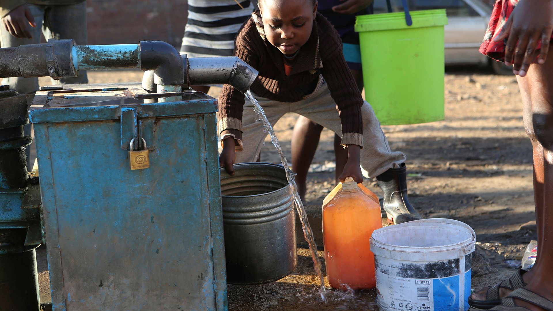Ein Kind füllt einen Eimer mit Wasser auf. | dpa